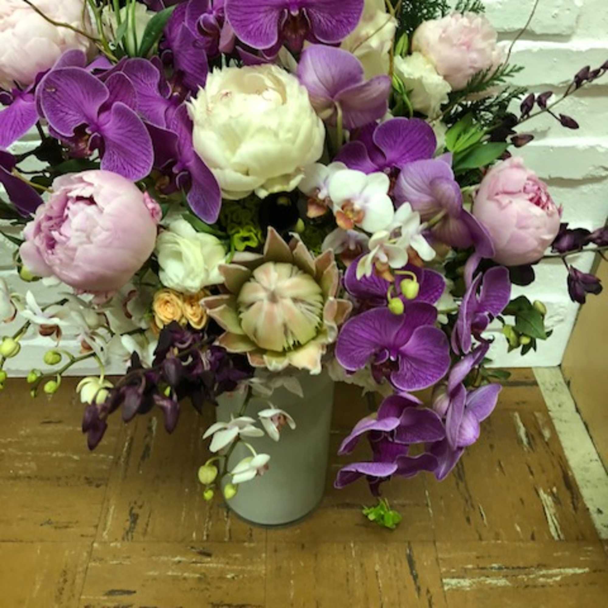Bouquet of purple orchids and pale pink peonies in a white vase