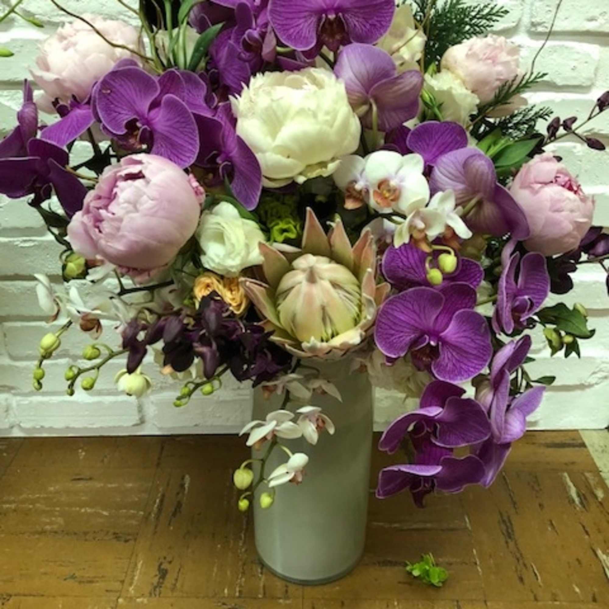 Purple orchids and pale peonies arranged in a tall vase