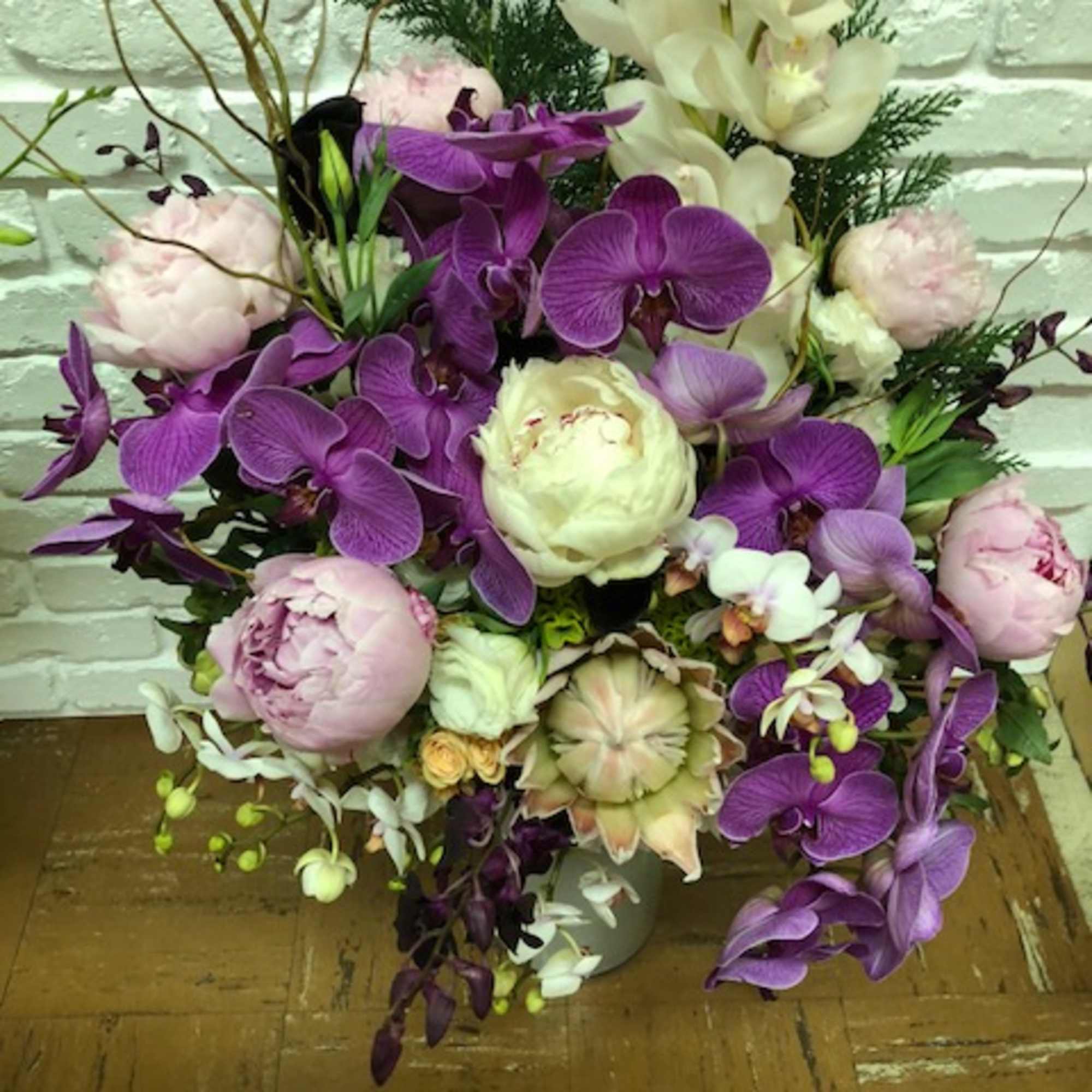Purple orchids and pale pink peonies arranged in a vase