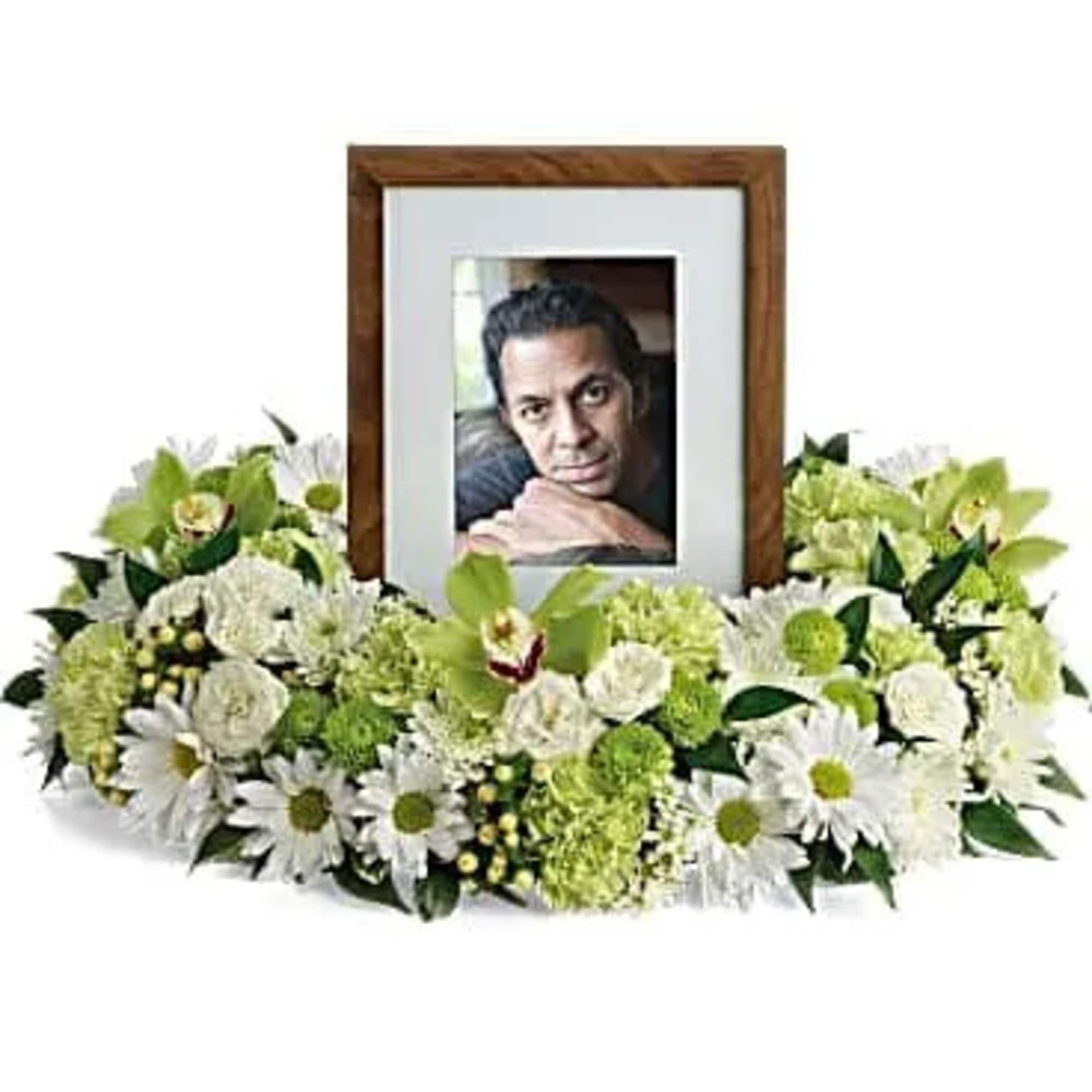 Low white and green floral ring surrounding a wooden picture frame with a portrait