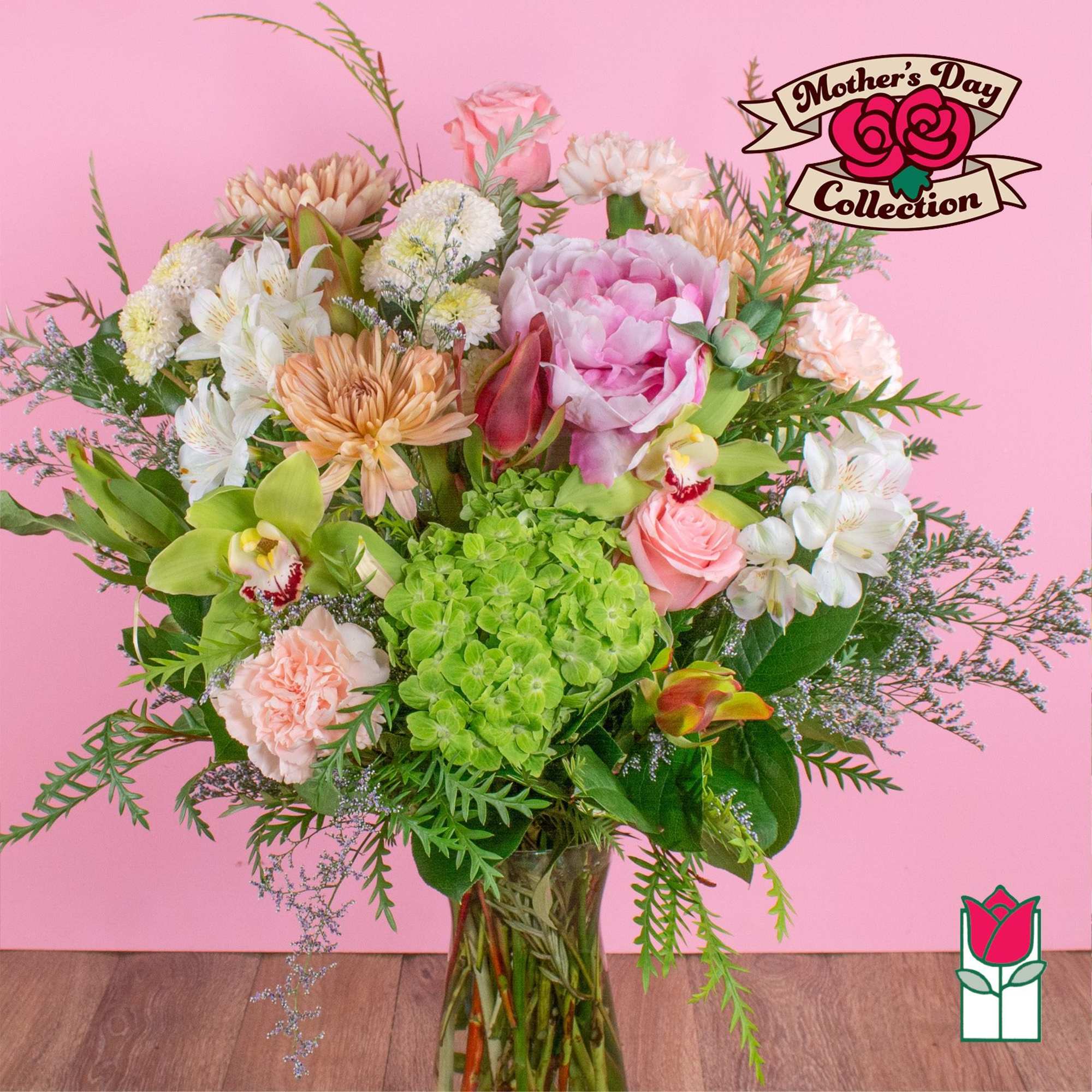 Tall mixed bouquet of pink peony, roses, green hydrangea, and orchids in a clear glass vase.