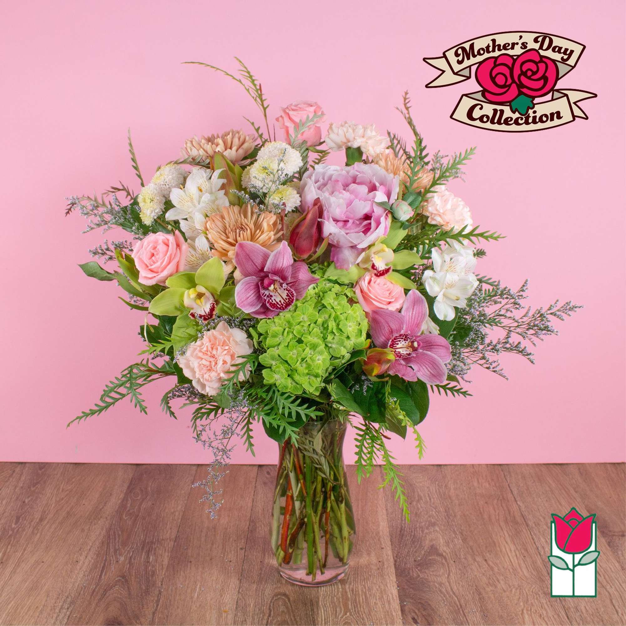 Tall mixed bouquet of pink blooms, orchids and green hydrangea in a clear glass vase.