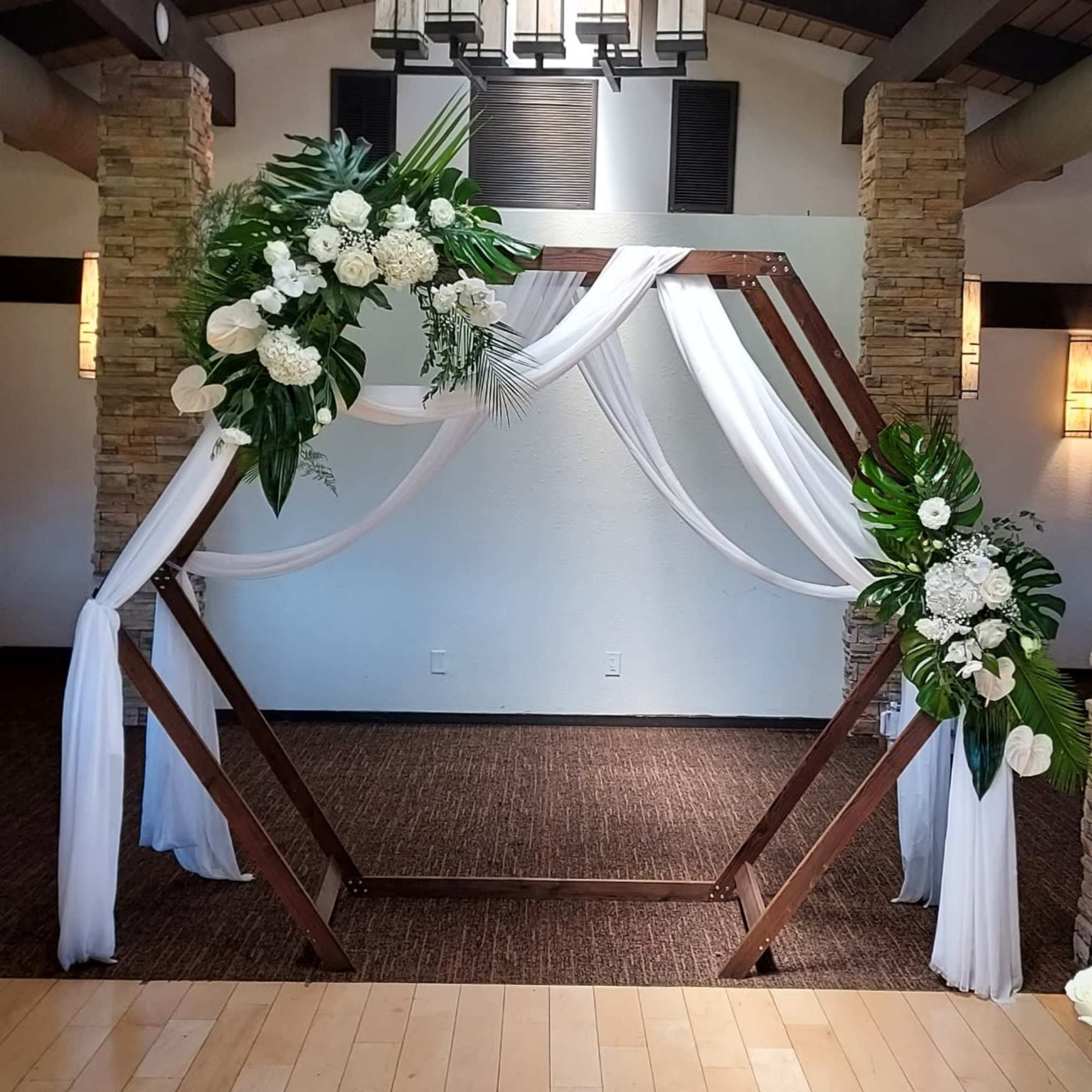 White and green wedding arches adorned with dendrobium orchids, roses, hydrangeas and