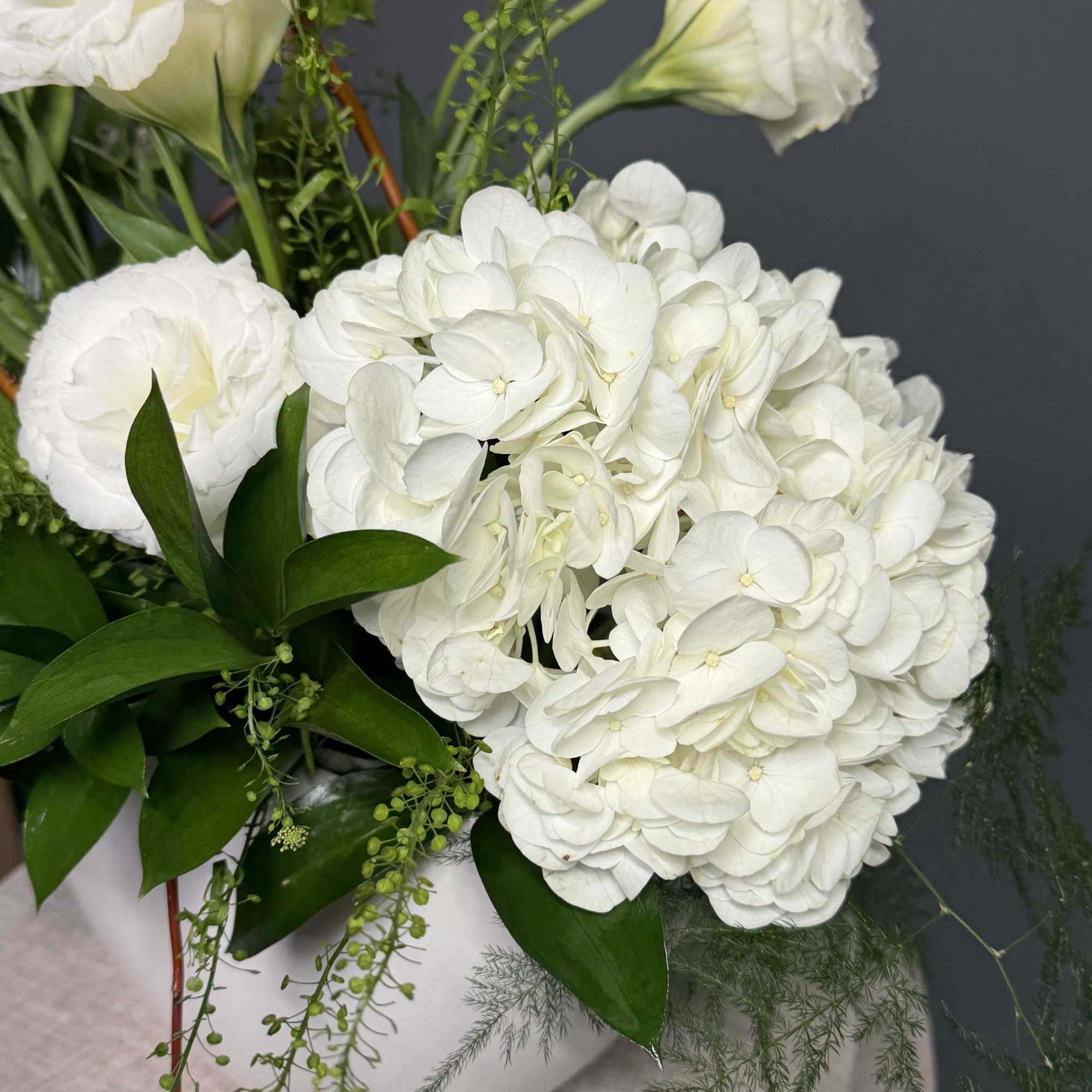 Low white ceramic bowl arrangement with white hydrangeas and lisianthus