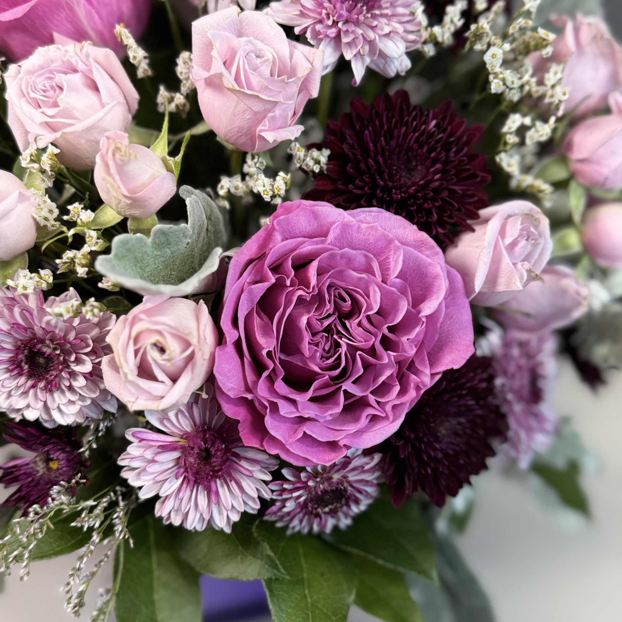 Arrangement of pink roses and purple chrysanthemums in a purple vase