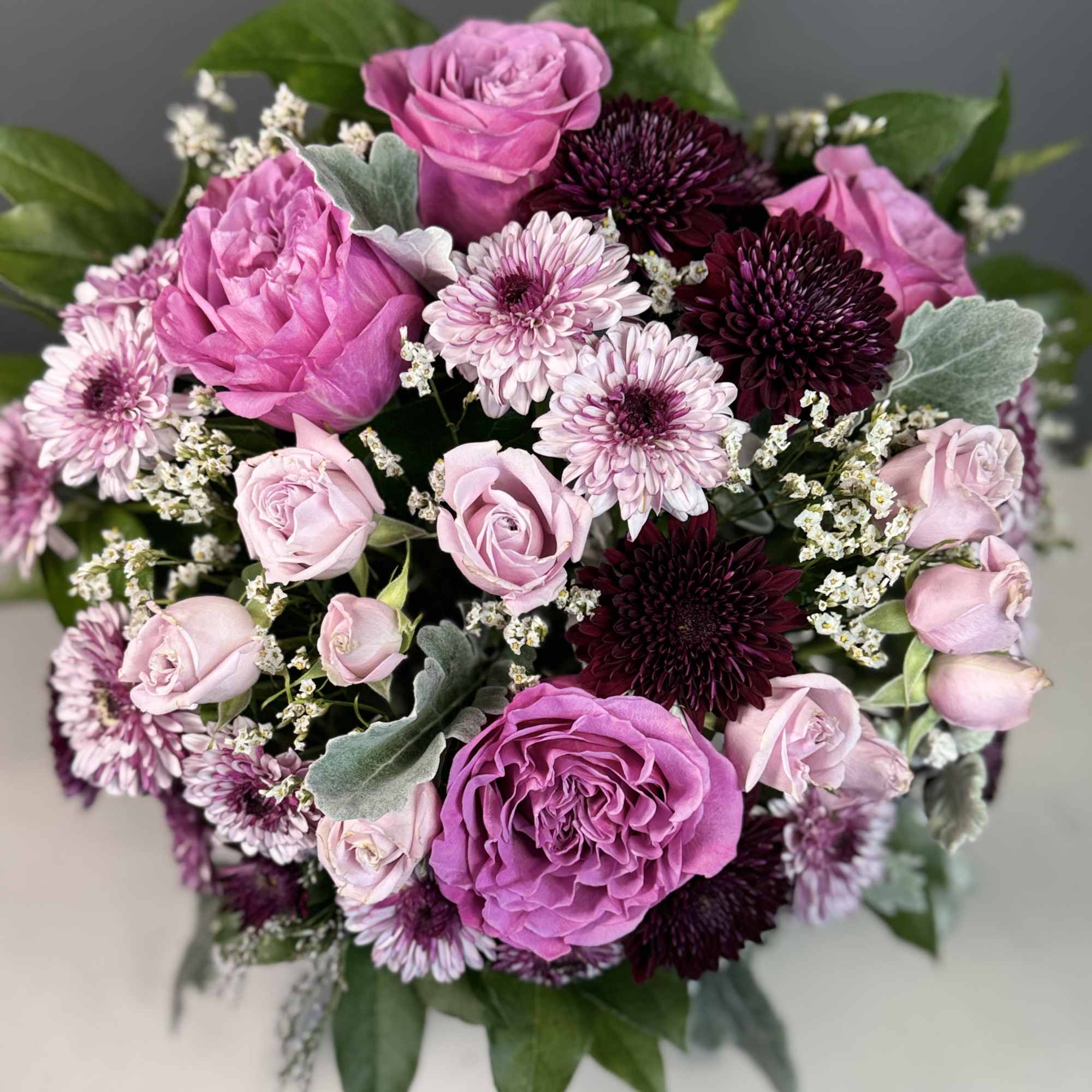Round bouquet of pink roses and burgundy chrysanthemums with pale pink mums