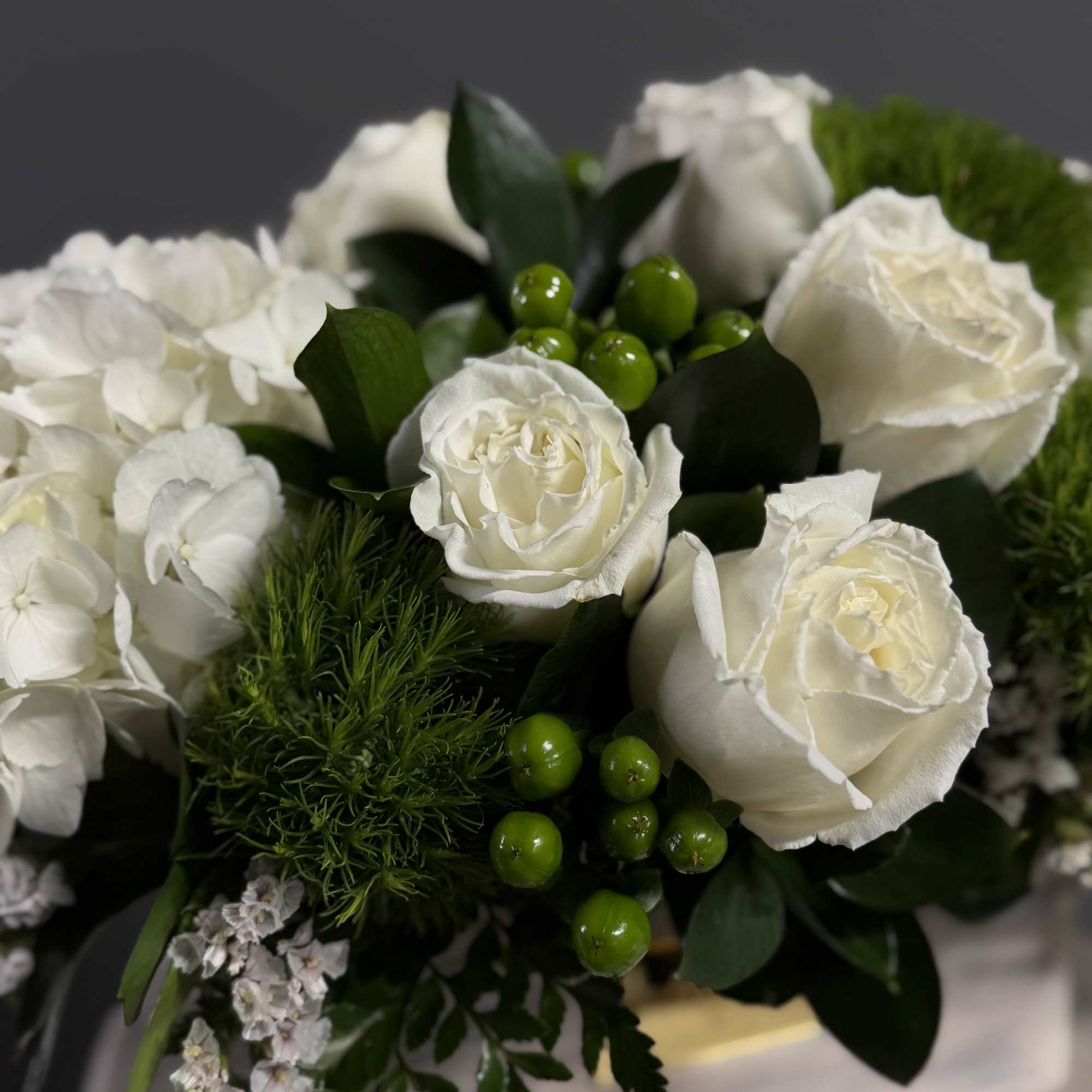 This crisp white and green arrangement includes roses, dianthus, and hydrangeas. The