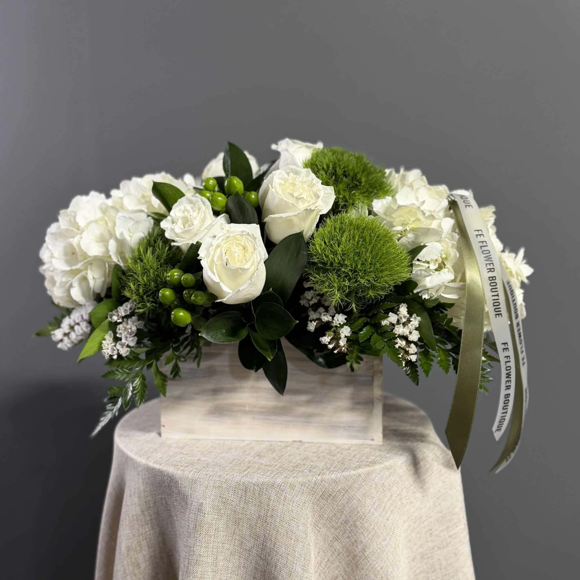 This crisp white and green arrangement includes roses, dianthus, and hydrangeas. The