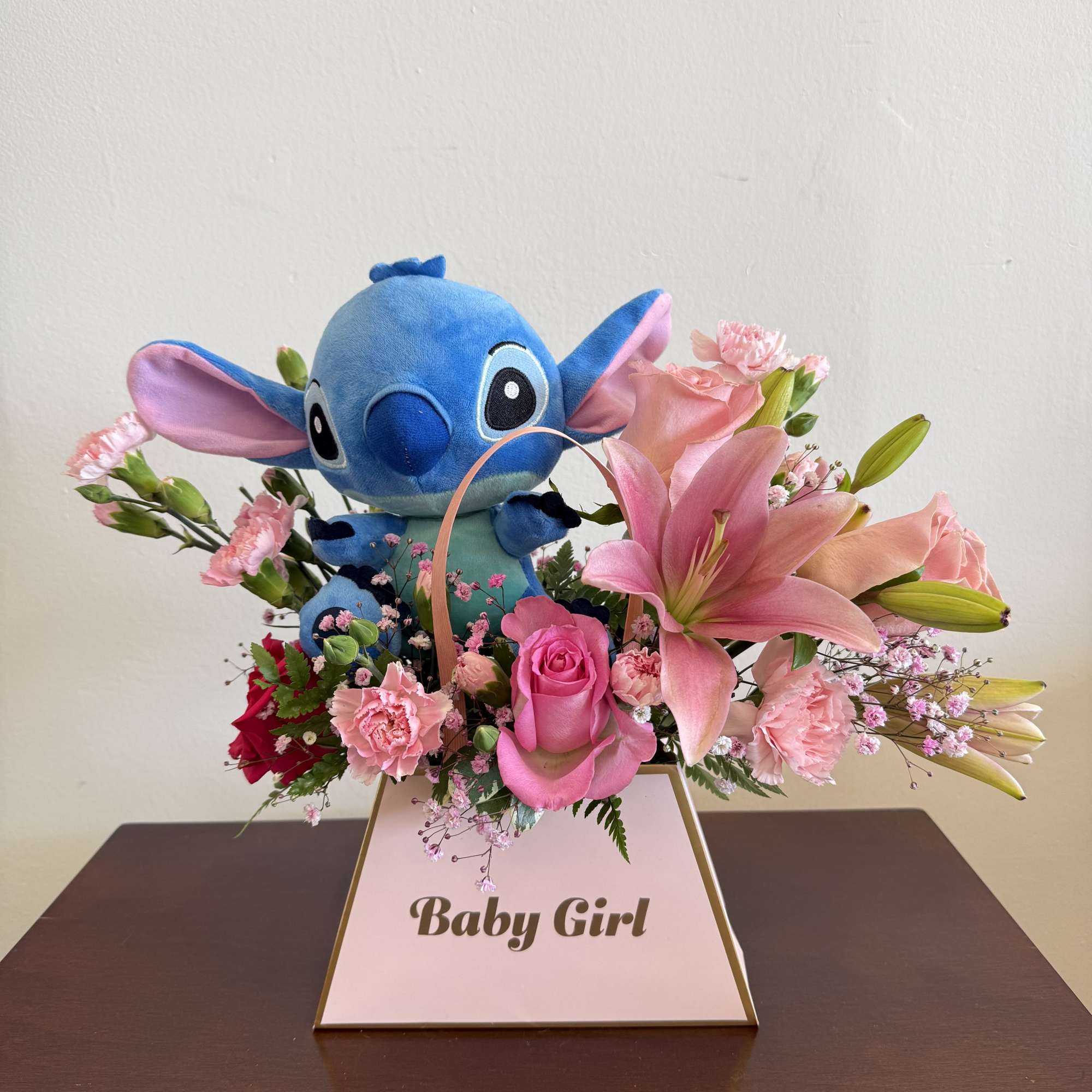 Pink lily and rose arrangement with blue plush toy in a Baby Girl box.
