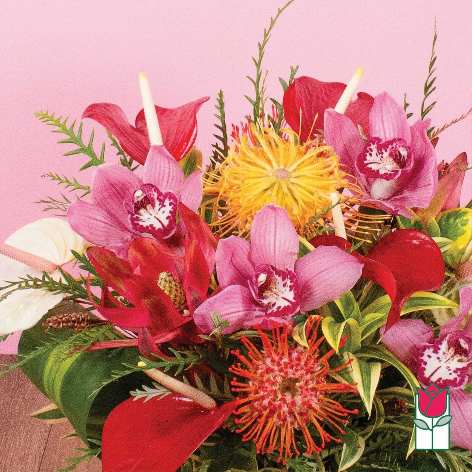 Tropical arrangement with pink orchids, red blooms, and yellow pincushion protea in a compact design