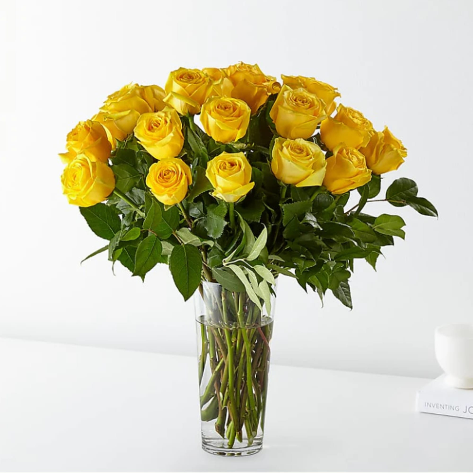 Tall bouquet of yellow roses arranged in a clear glass vase with water