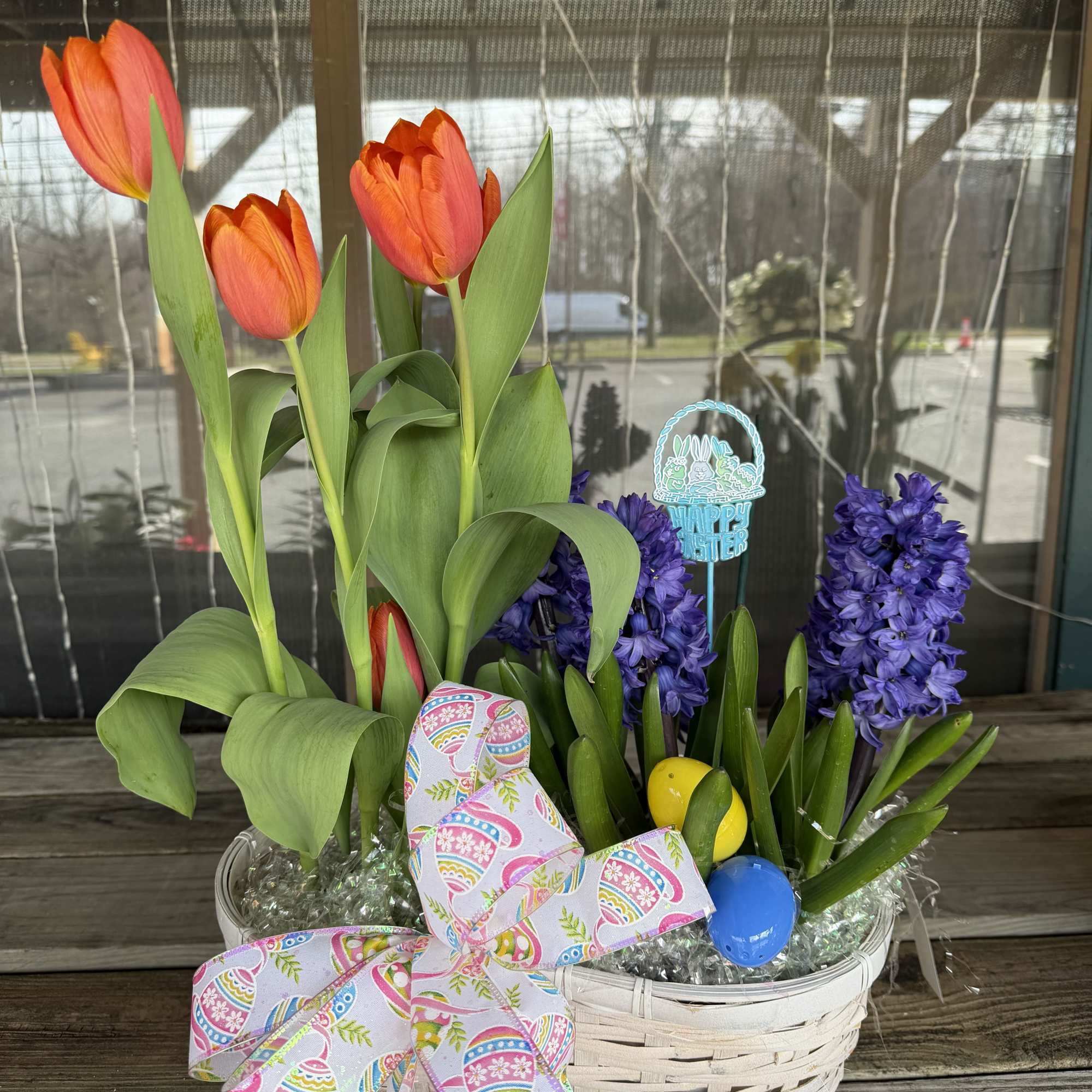 A variety of Easter Plants arranged in a basket with Easter accents.