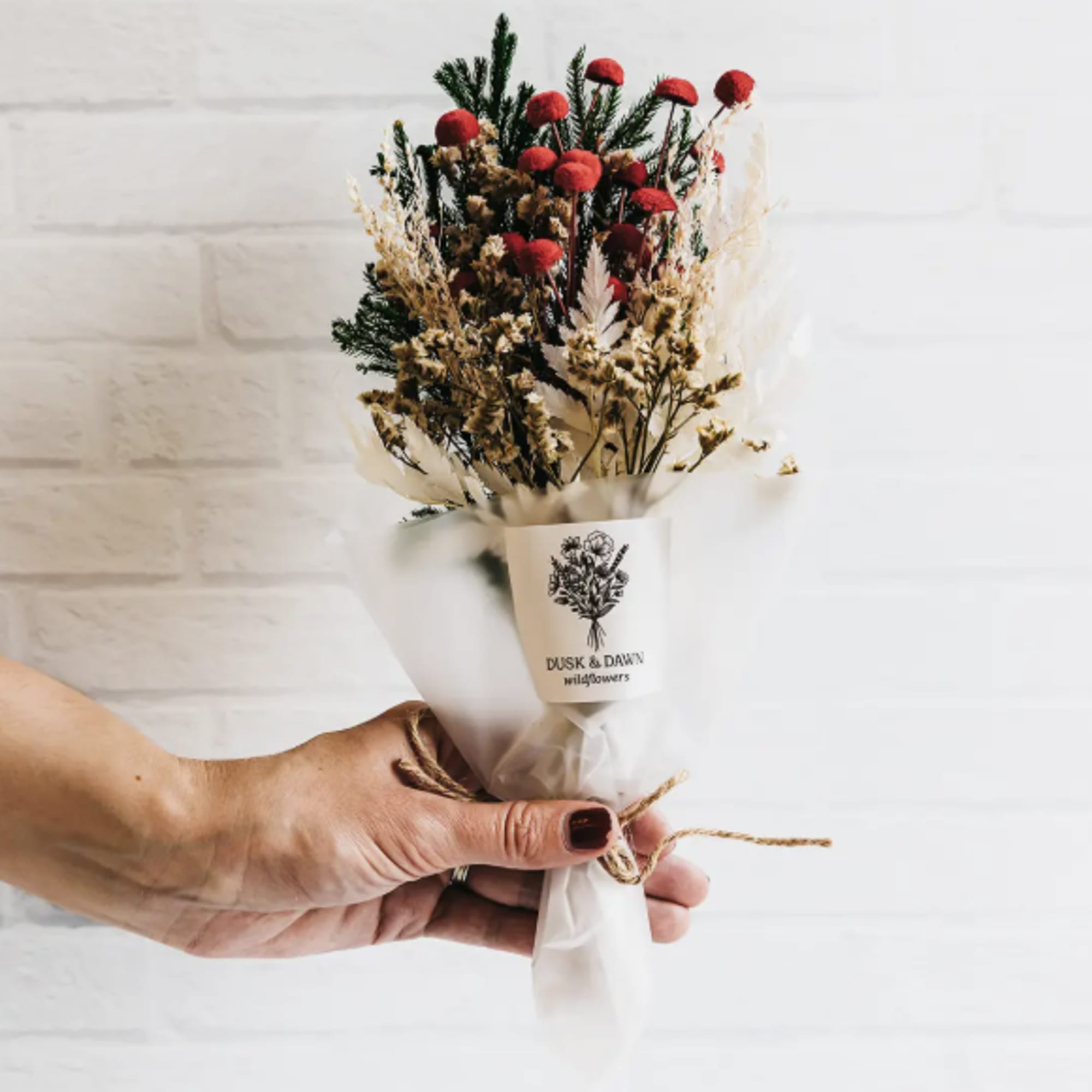 Small dried flower bouquet with red blooms wrapped in white paper