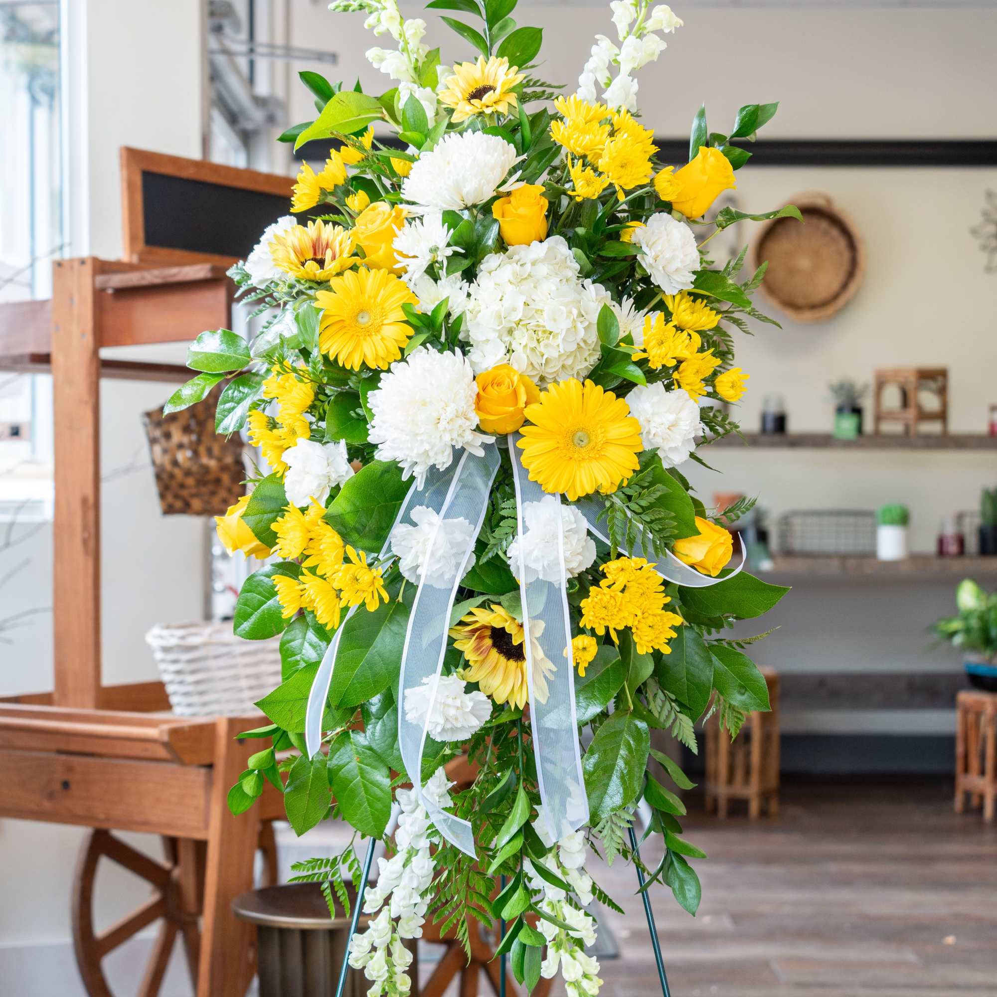 And easel arrangement featuring yellow gerber daisy's, yellow roses, sunflowers, yellow cremon