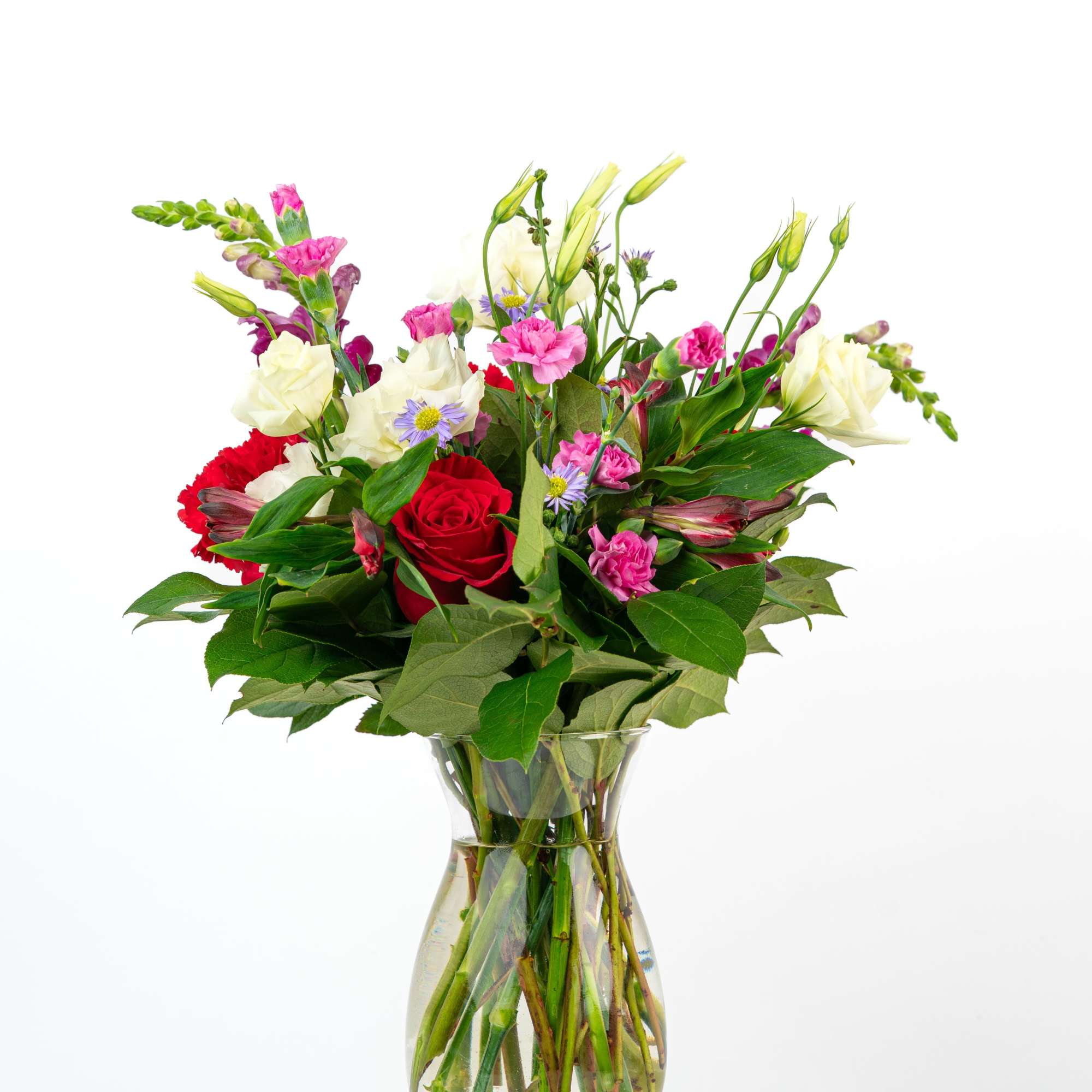 Mixed bouquet of red, pink, and white flowers in a clear glass vase