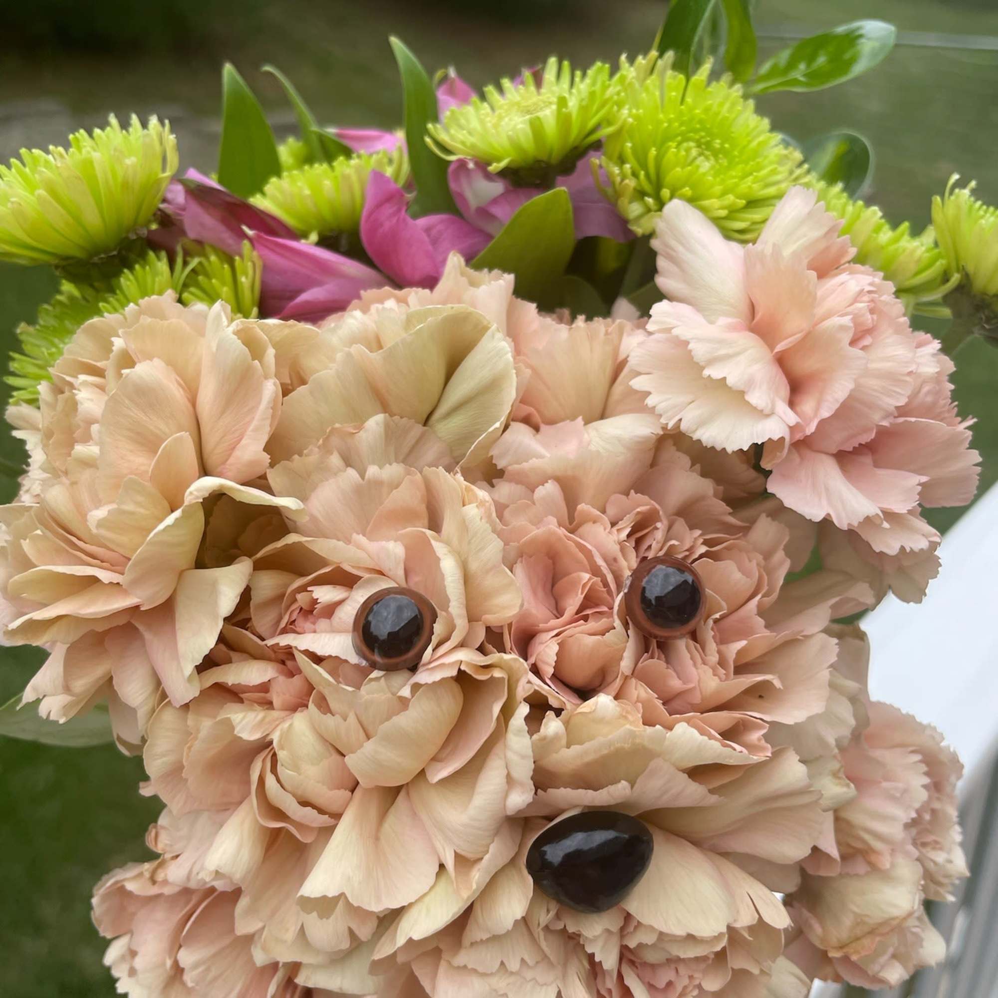 Dog-shaped arrangement of peach carnations with green mums and pink flowers in a football vase