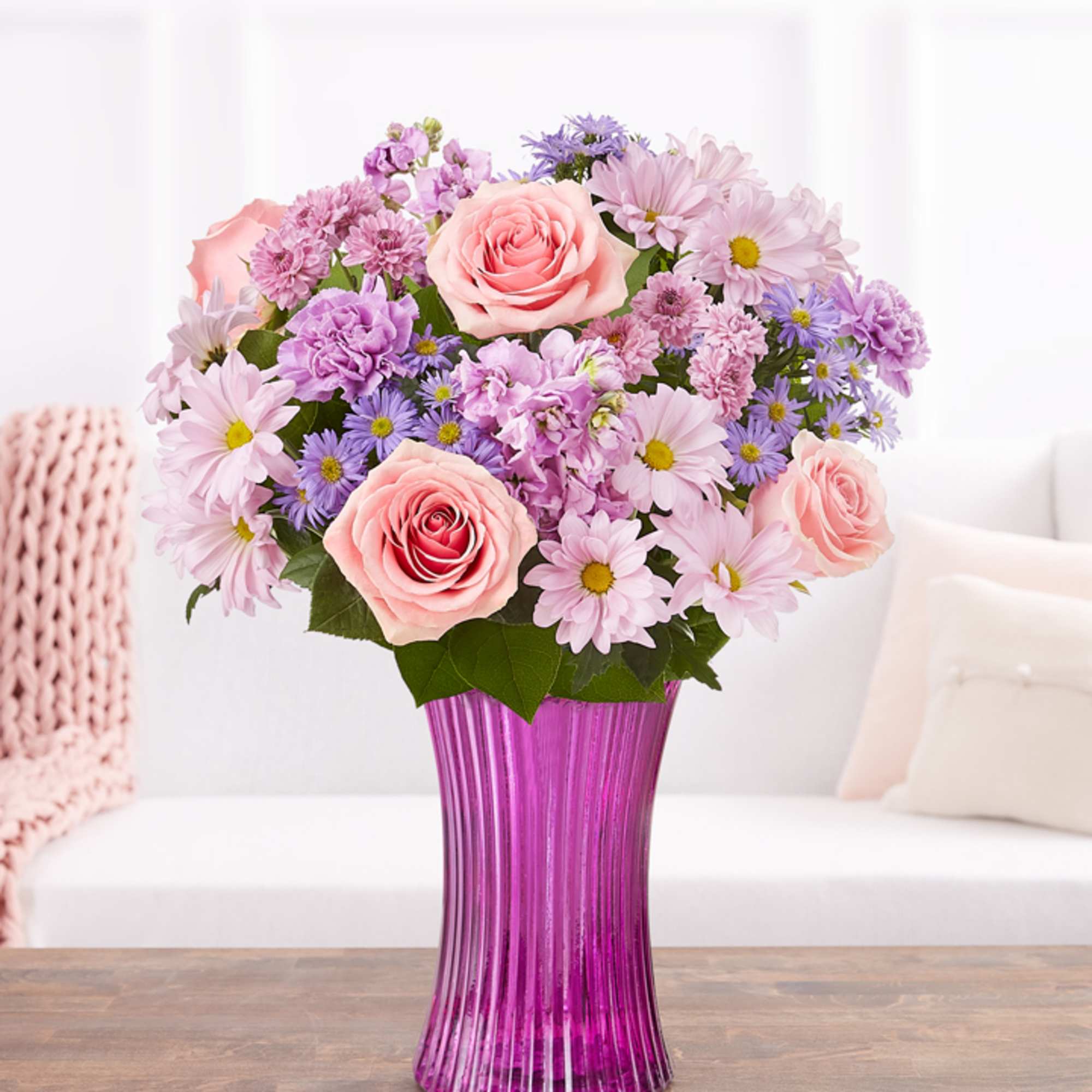 Pink roses and lavender daisies in a purple glass vase