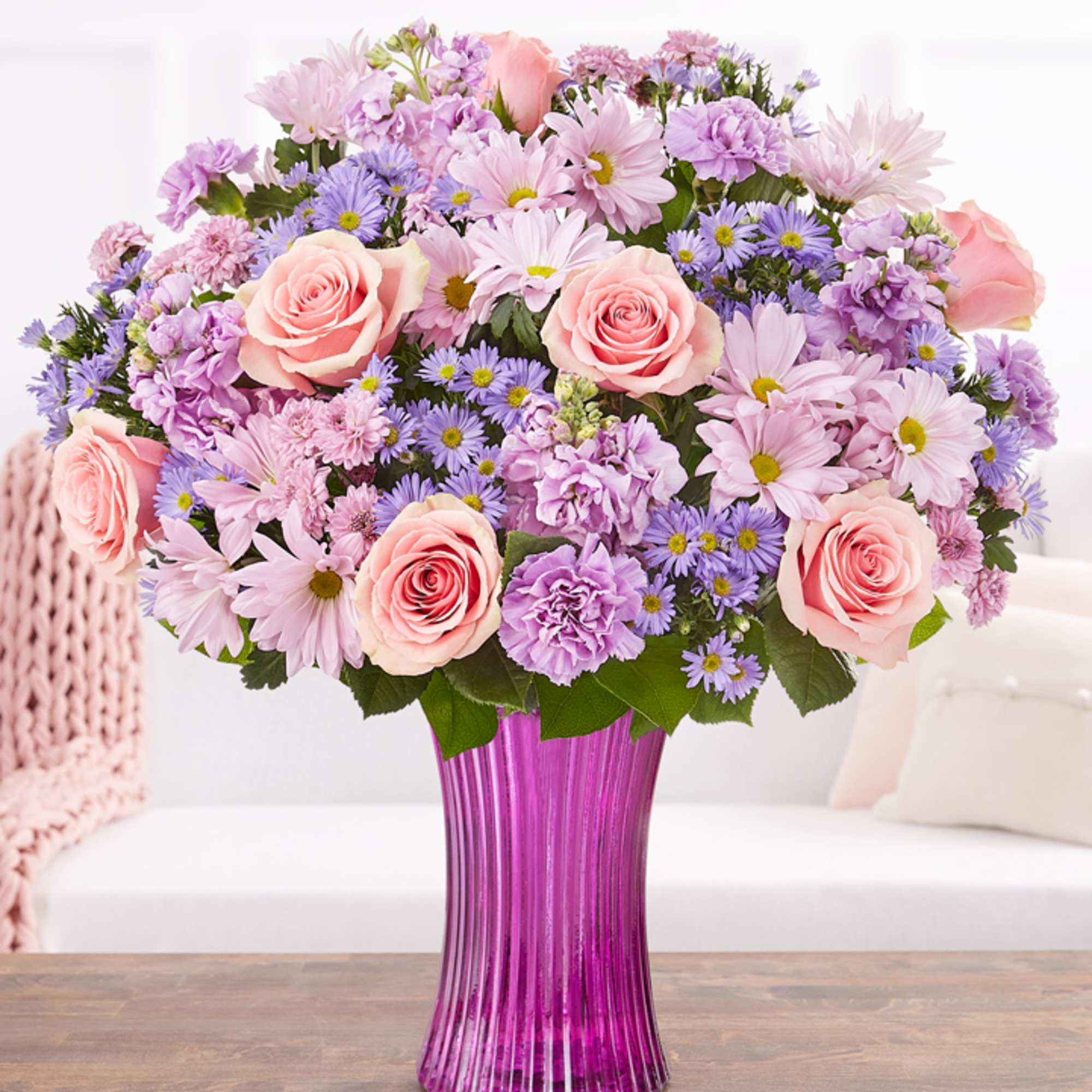 Pink roses and lavender daisies in a purple glass vase