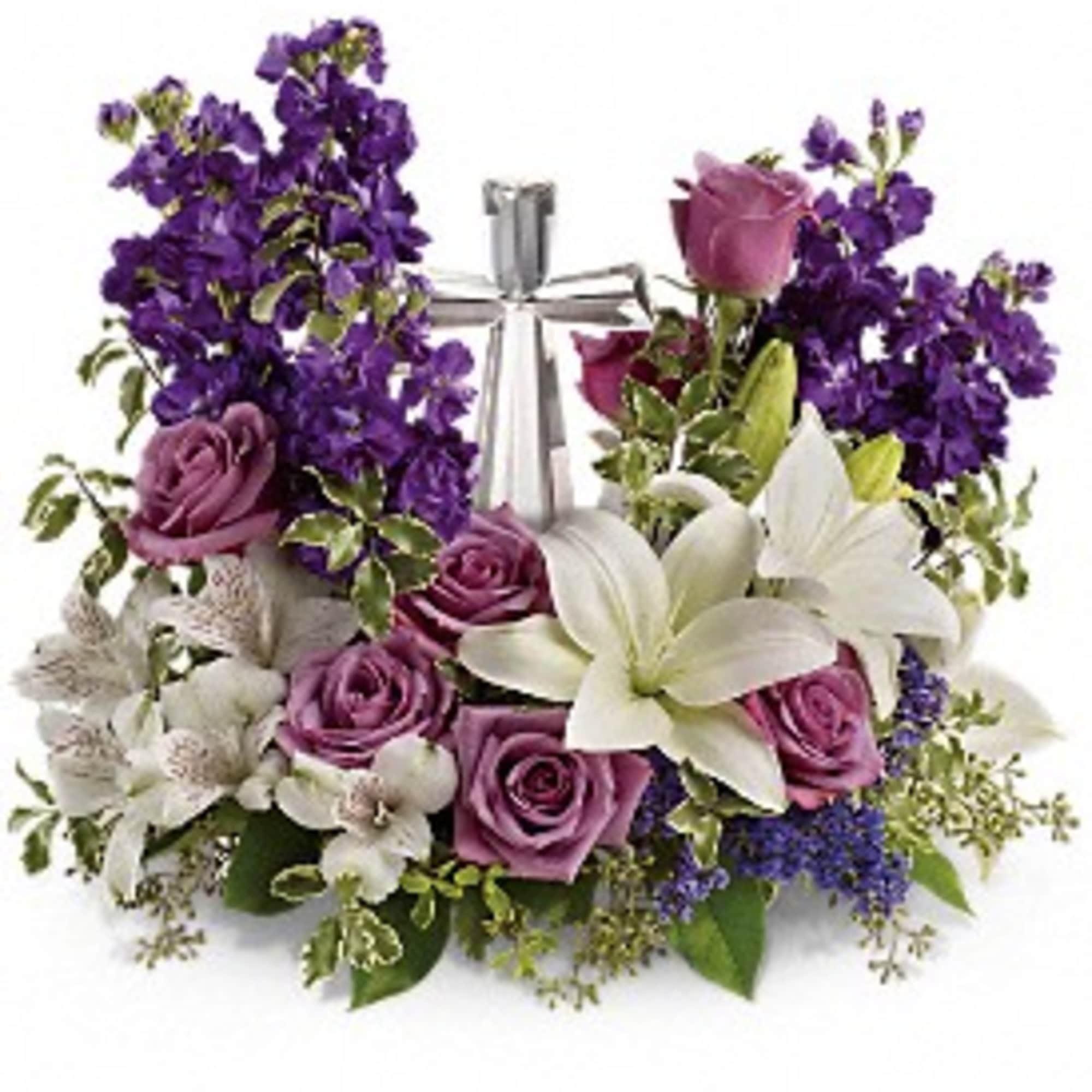 Arrangement of purple flowers, lavender roses, and white lilies surrounding a silver cross.