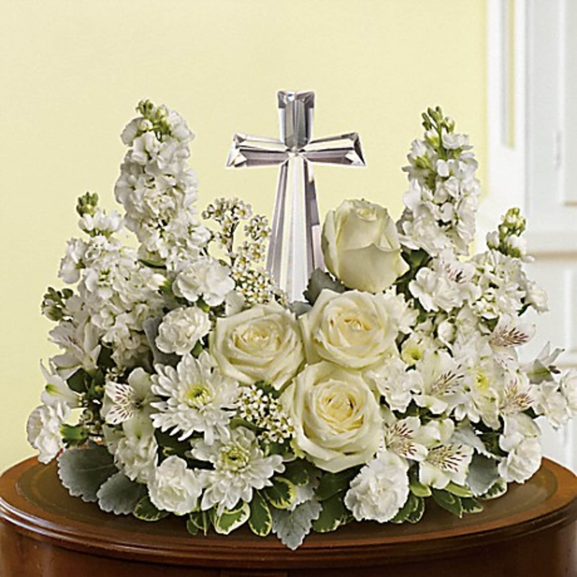 White rose and mum arrangement with a crystal cross centerpiece on a wooden table.