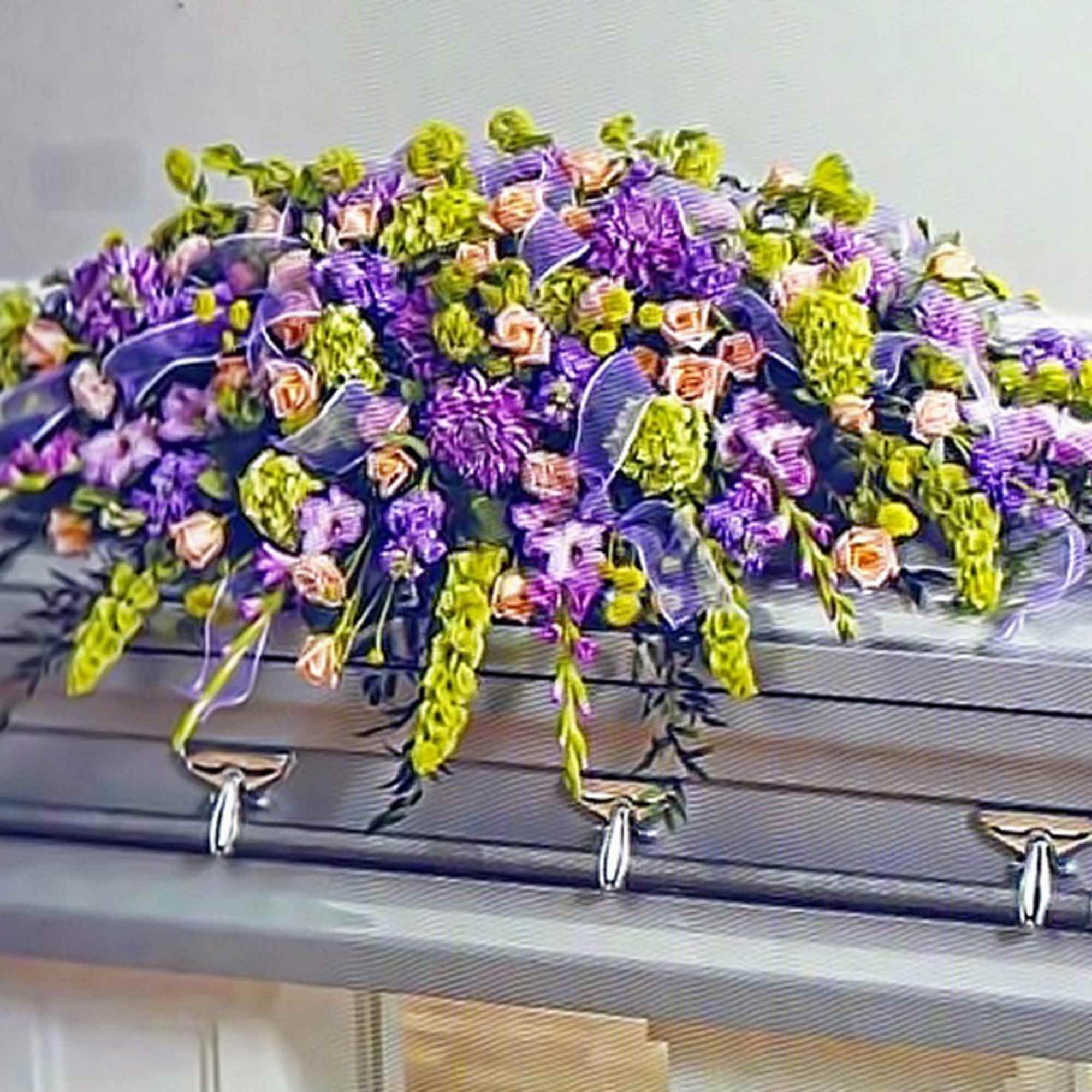 Purple, green, and peach casket spray of mixed flowers arranged on a silver casket