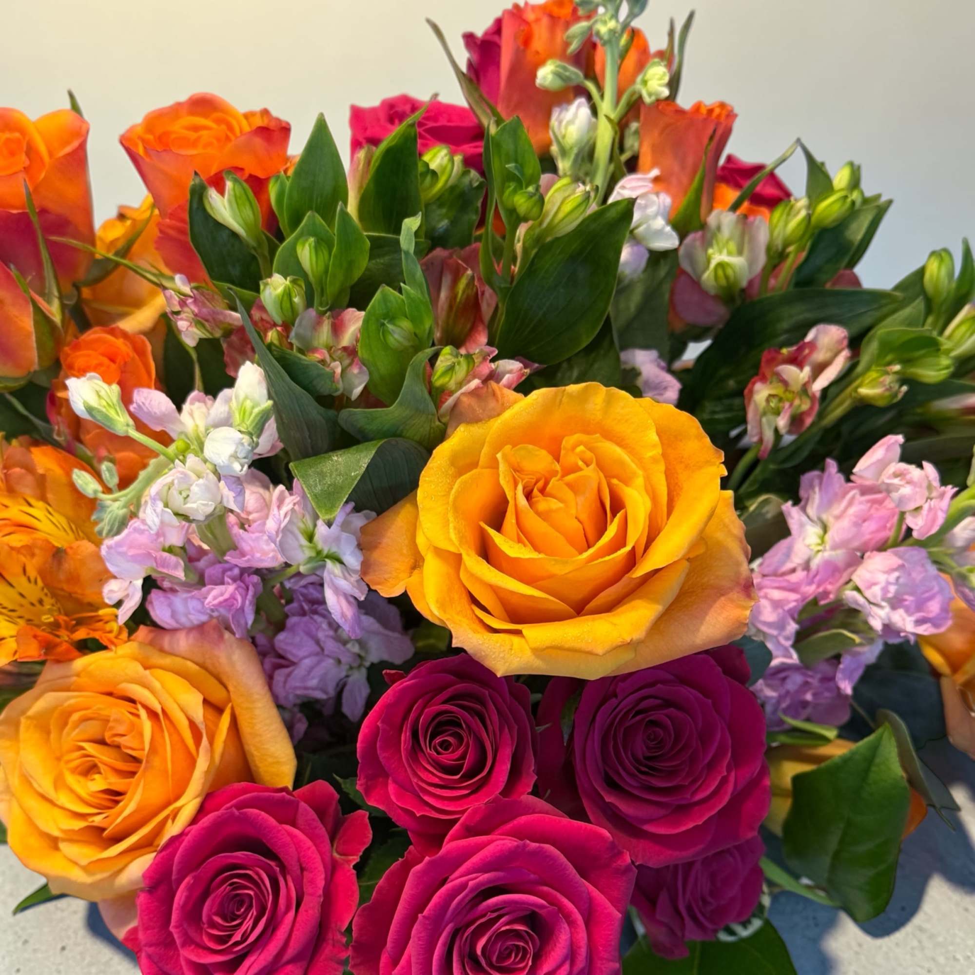 A vibrant cluster of yellow, orange, and deep pink roses crowns this