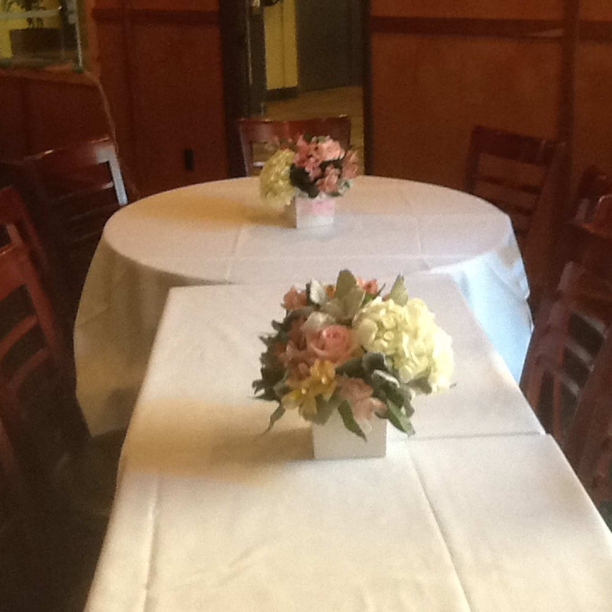 Pastel floral centerpieces in white cube vases on round and rectangular banquet tables.
