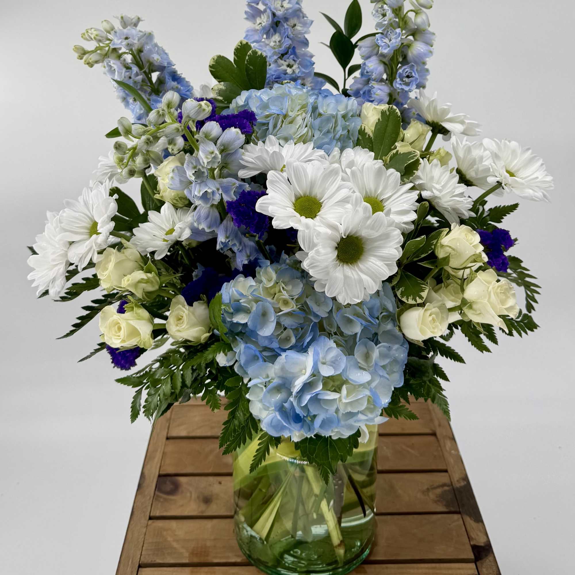 Immerse yourself in a tranquil oasis with our enchanting Sky-Blue flower arrangement