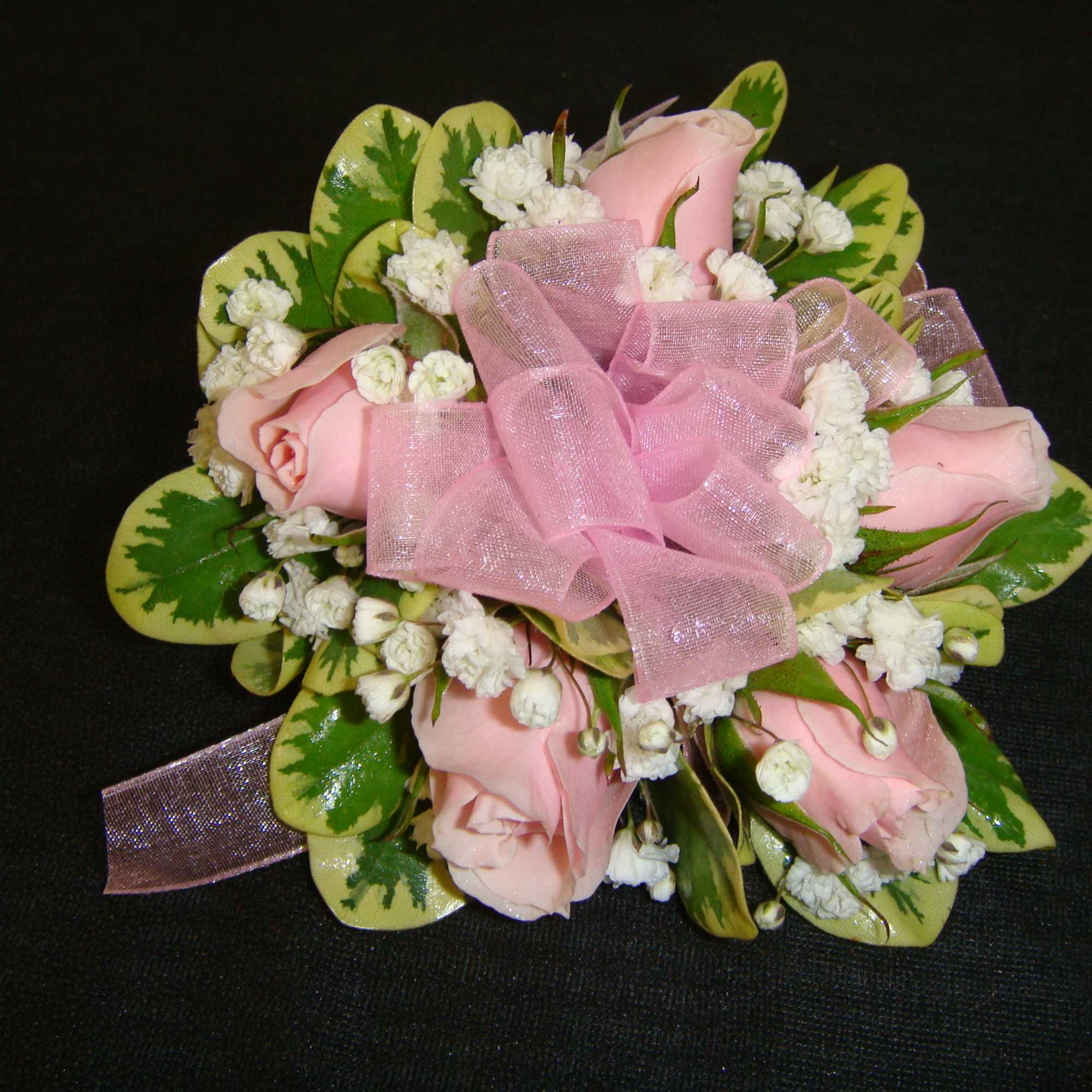 Pink rose corsage with white filler flowers and a pink ribbon