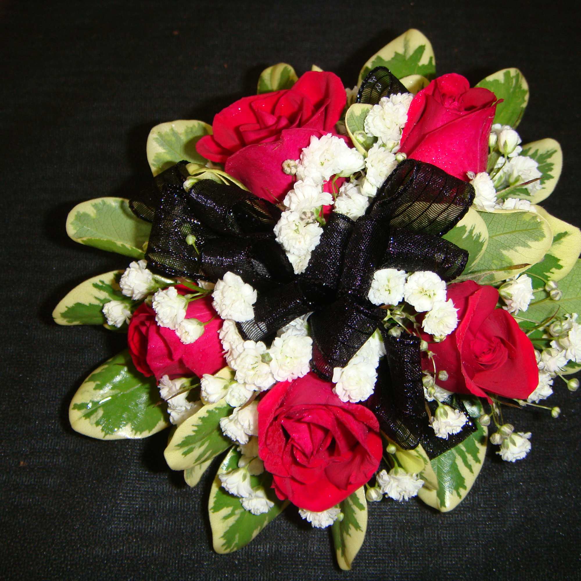 Small bouquet of red roses with white filler flowers and a black ribbon