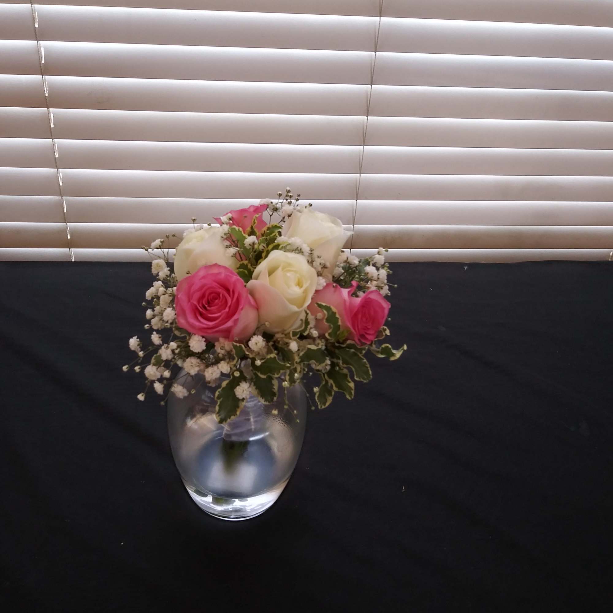 Pink and white roses arranged in a clear glass vase