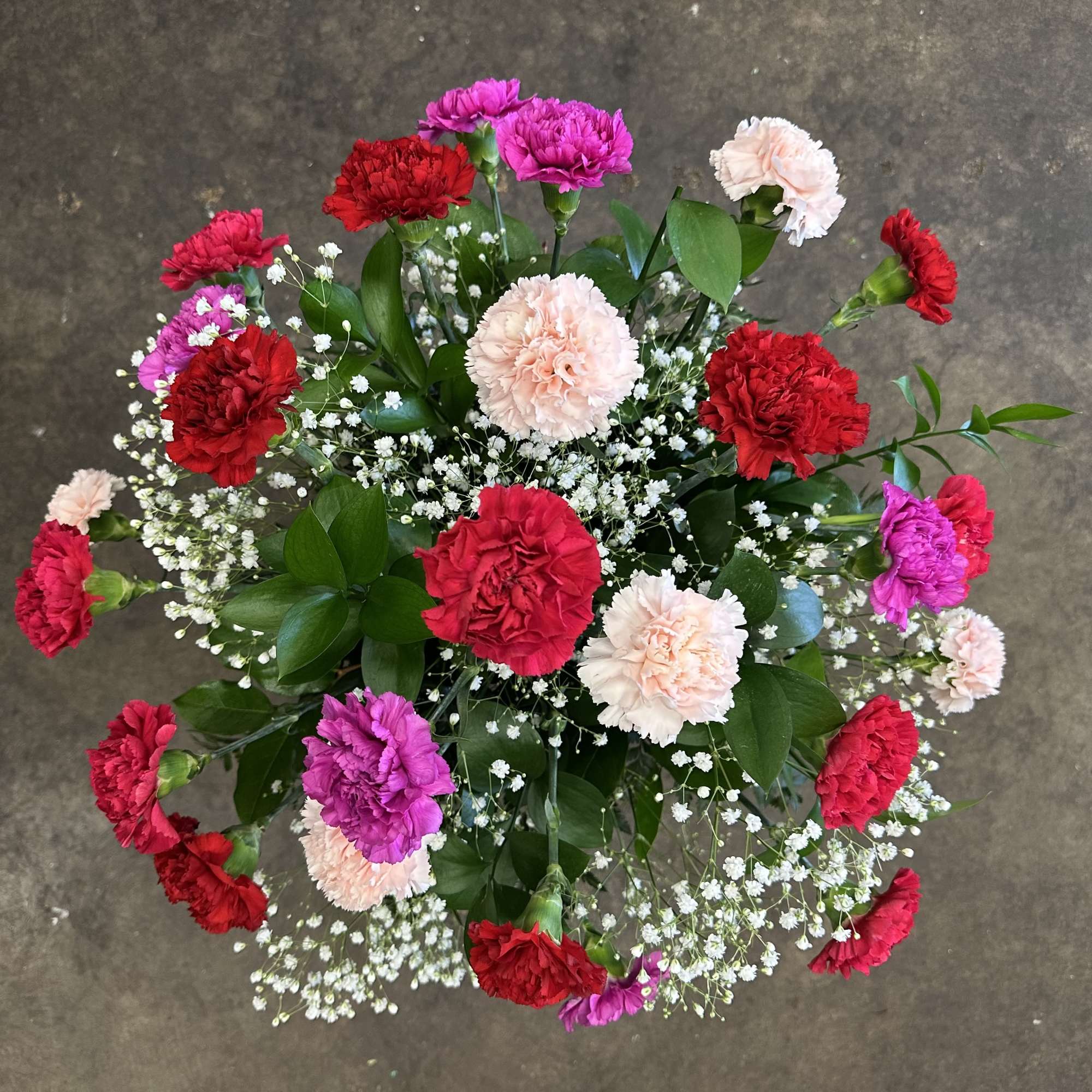 A full, airy arrangement of 25 premium carnations in assorted romantic colors