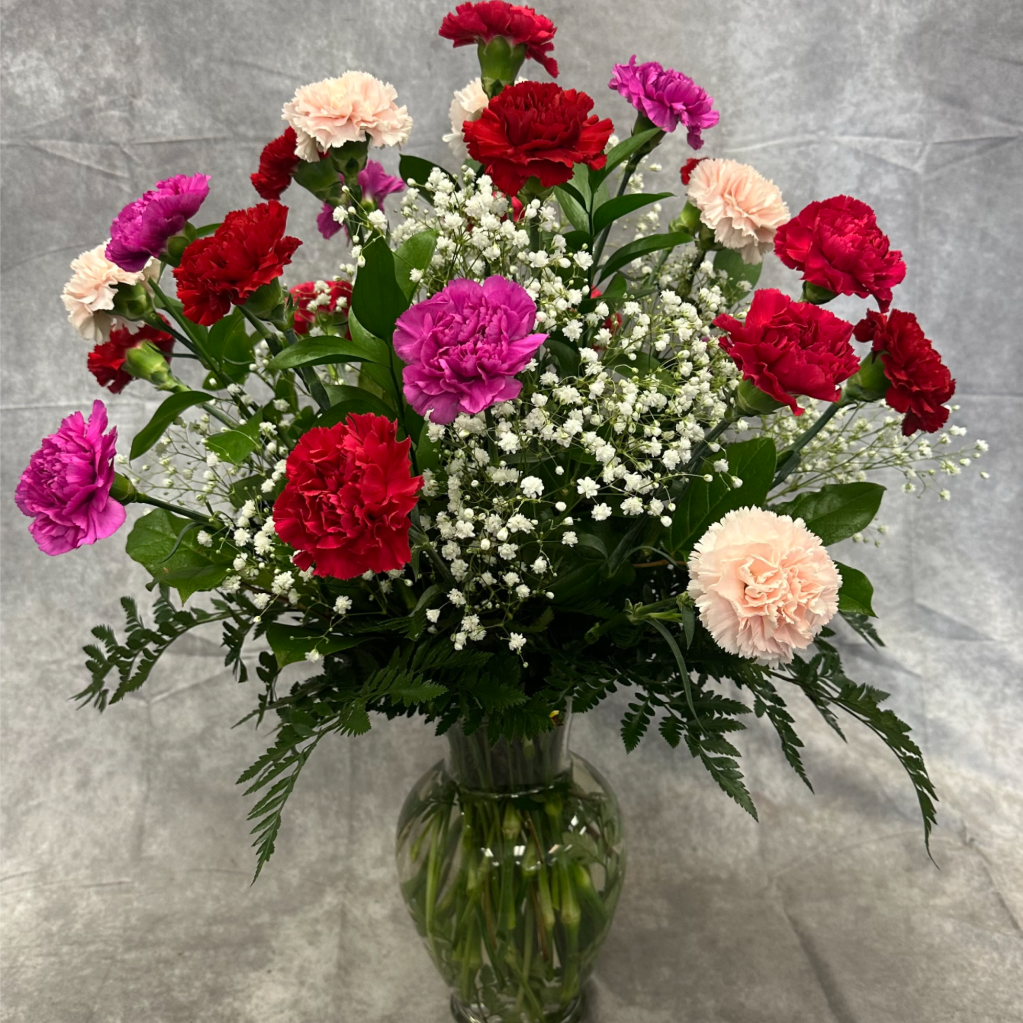 A full, airy arrangement of 25 premium carnations in assorted romantic colors
