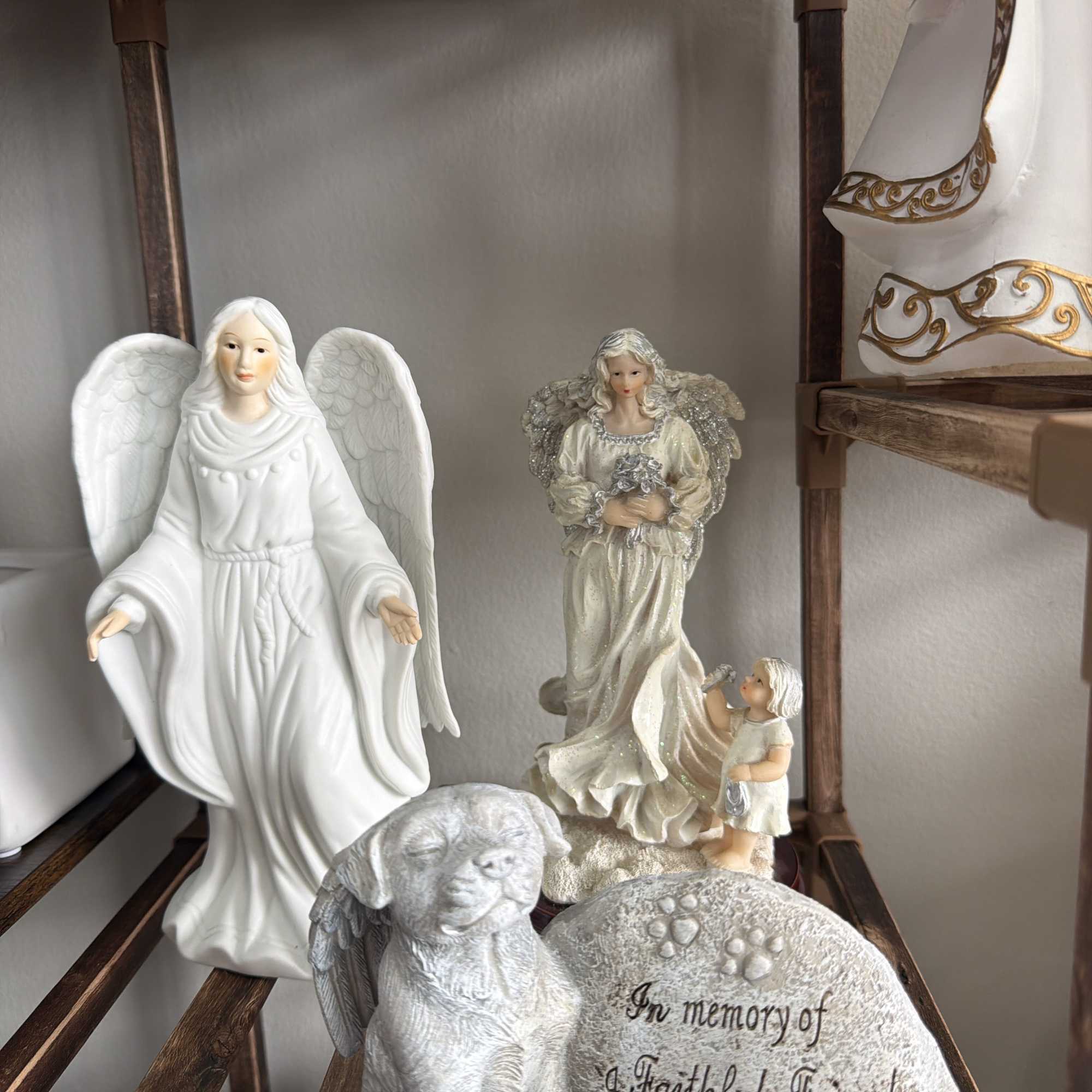 Memorial figurines with angels, a winged dog, and an engraved stone for a faithful friend and companion.