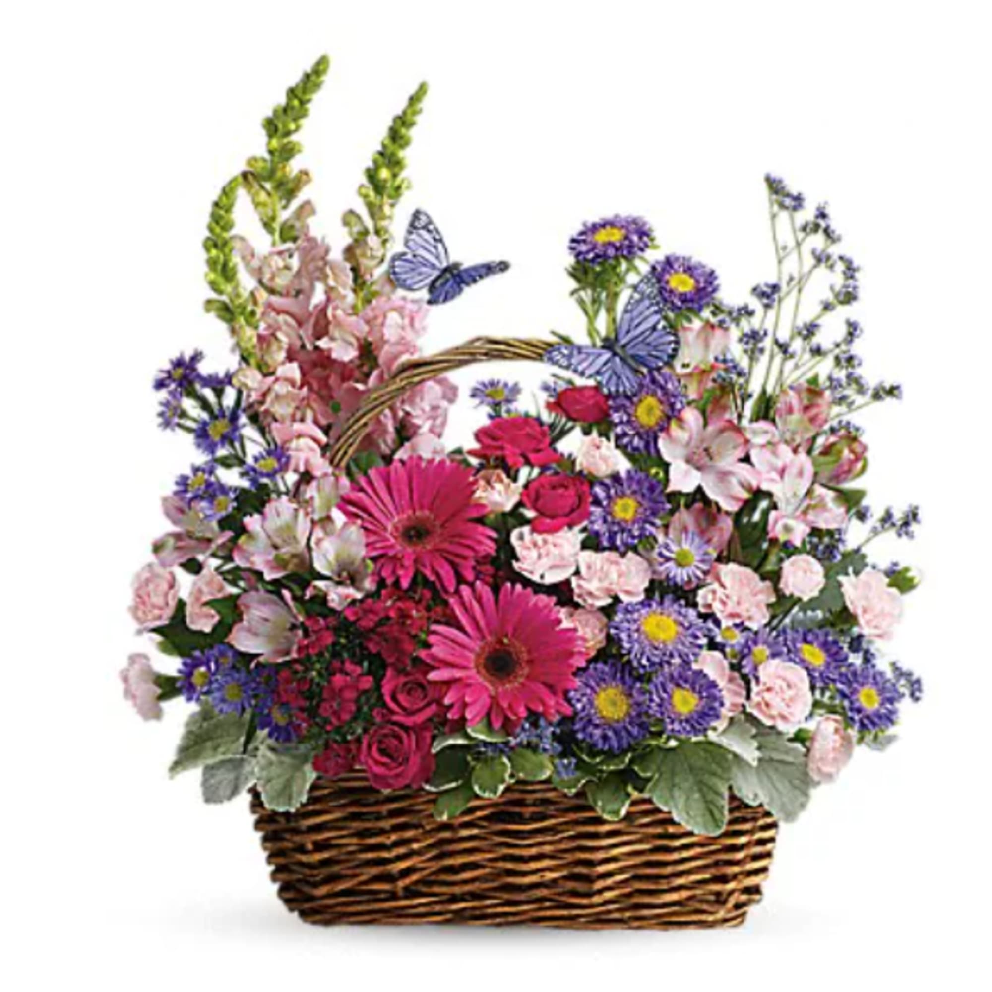 Wicker basket of pink gerberas, roses, and mixed purple and pink flowers with decorative butterflies.