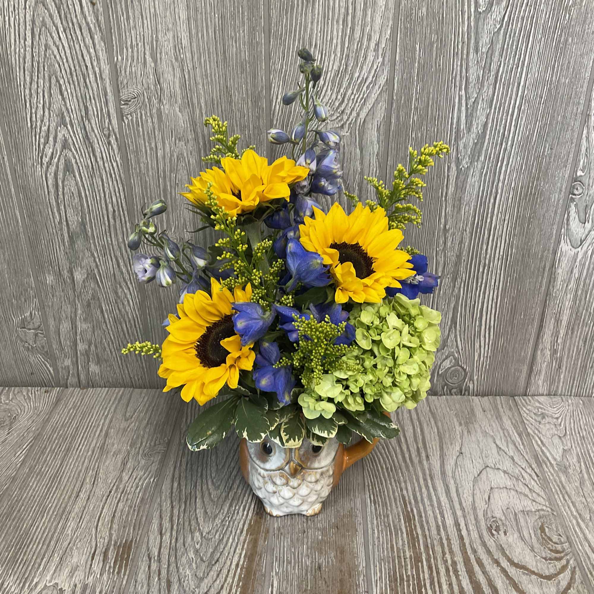 Ceramic owl mug filled with sunflowers. 