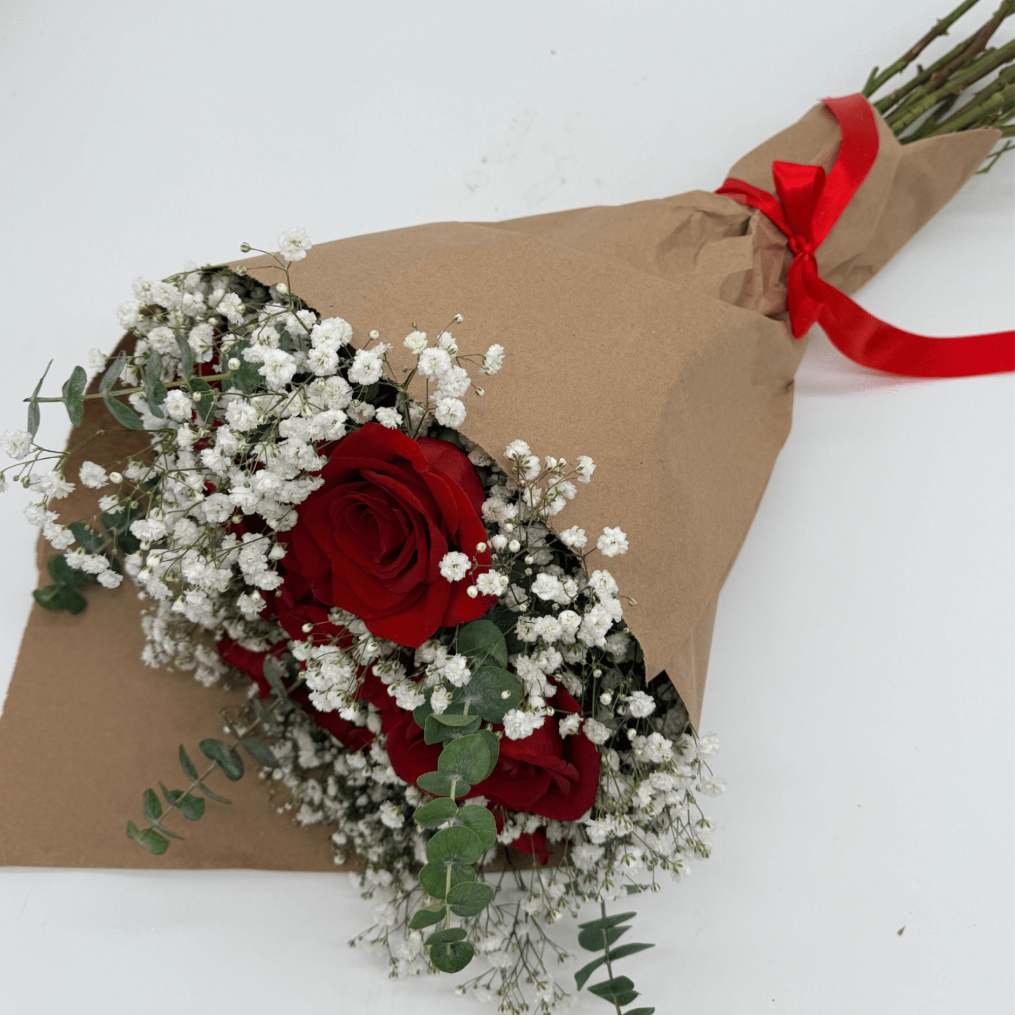 Red roses and white baby's breath wrapped in brown paper with a red ribbon