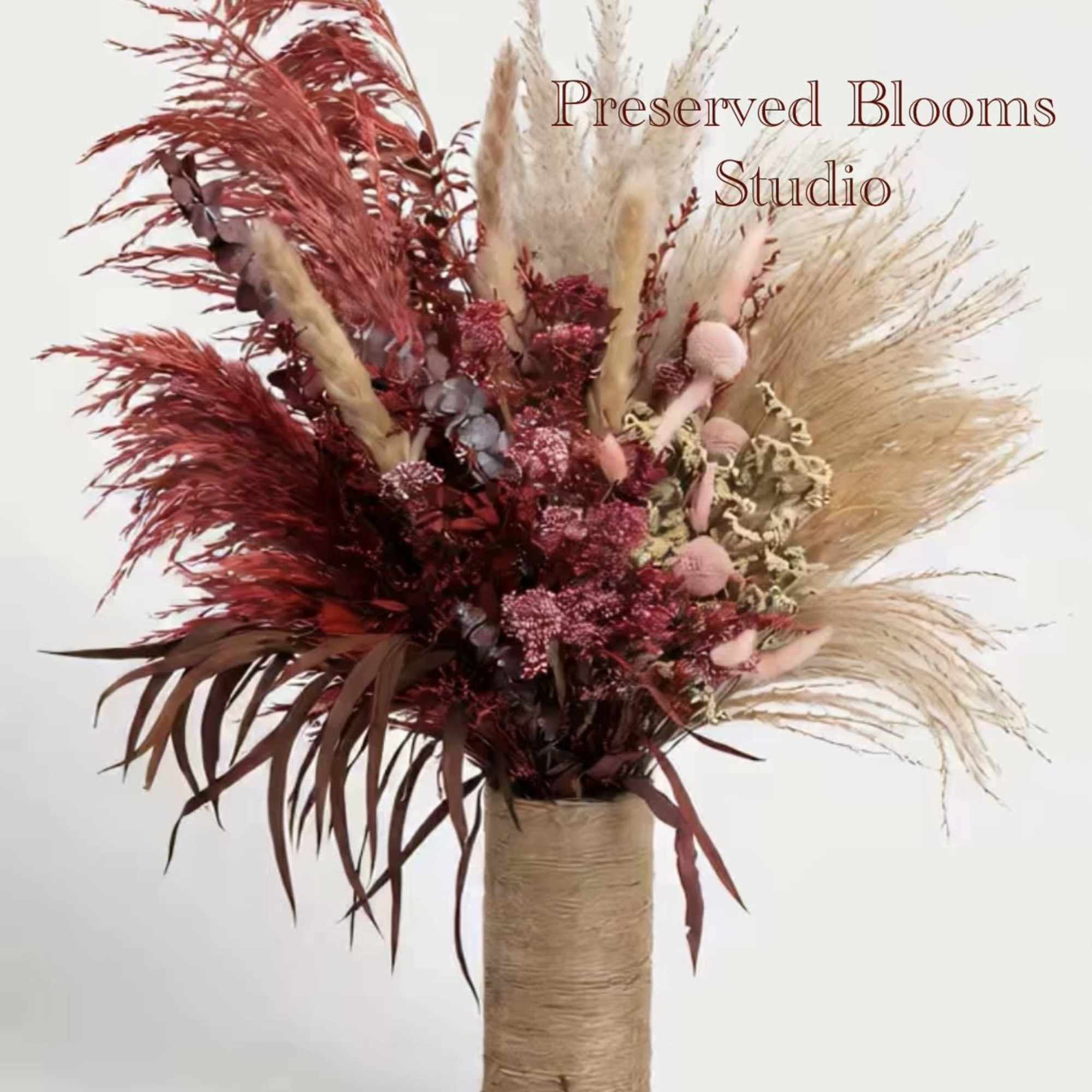 Tall dried arrangement of red and natural pampas in a twine-wrapped cylinder vase