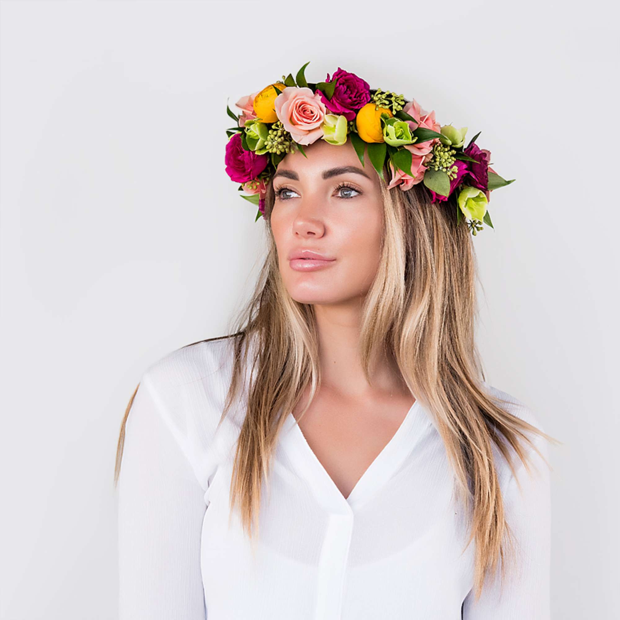 Bright flower crown with pink roses and yellow blooms worn by a woman