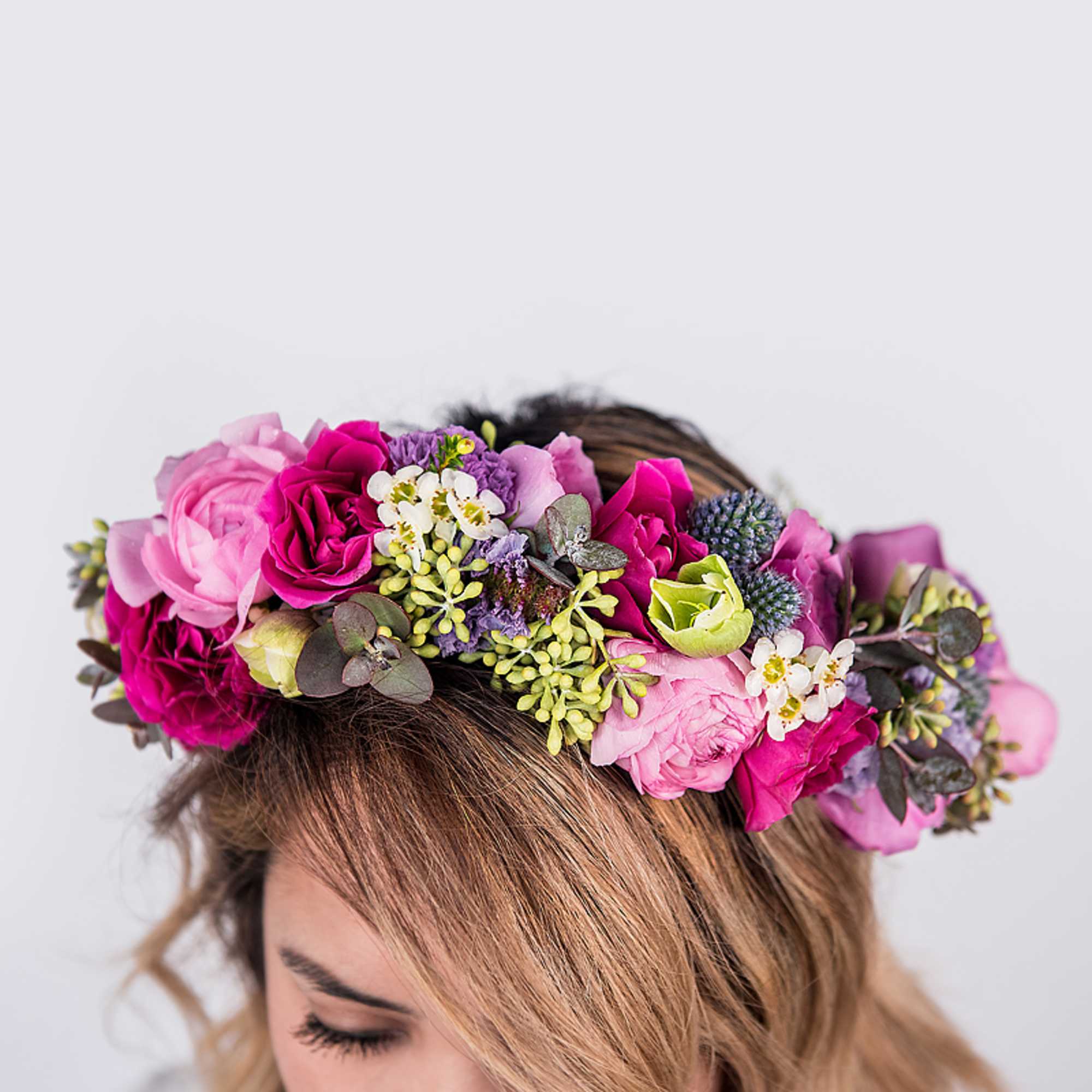 Bright pink and pastel flower crown worn on a person’s head against a light background