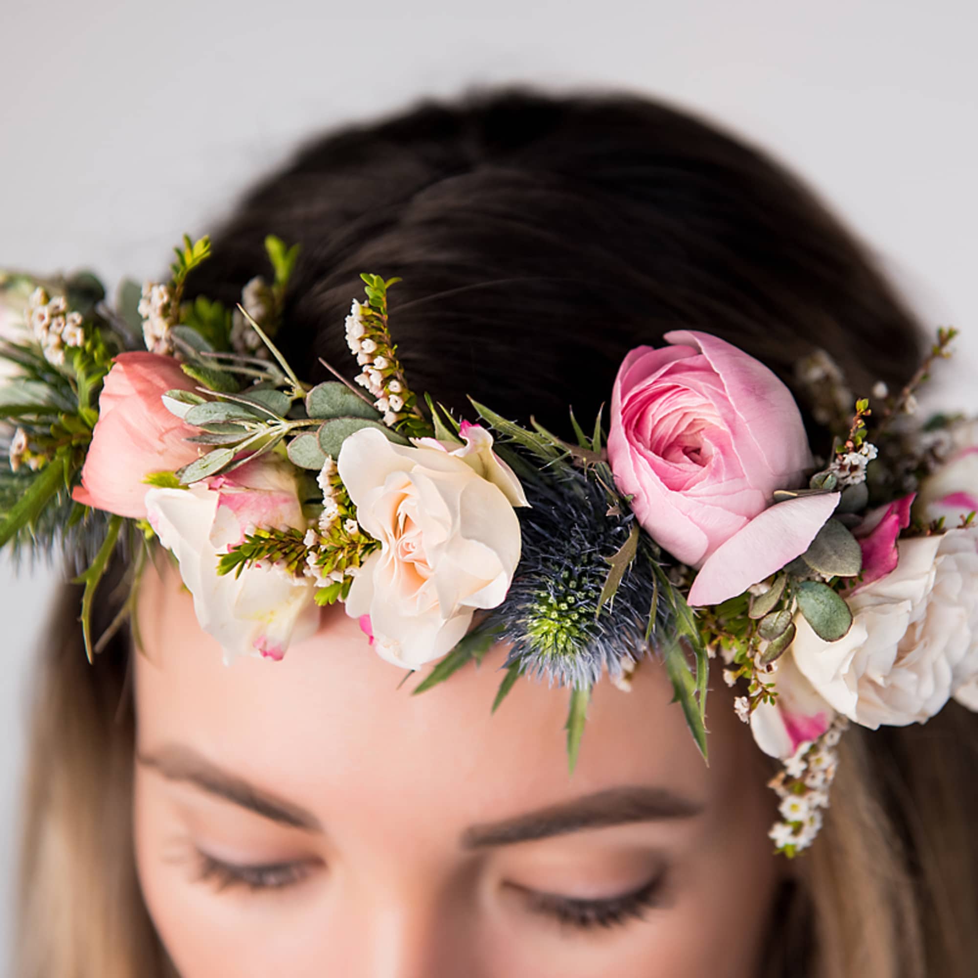 Floral crown of pink and ivory roses with greenery worn across the forehead
