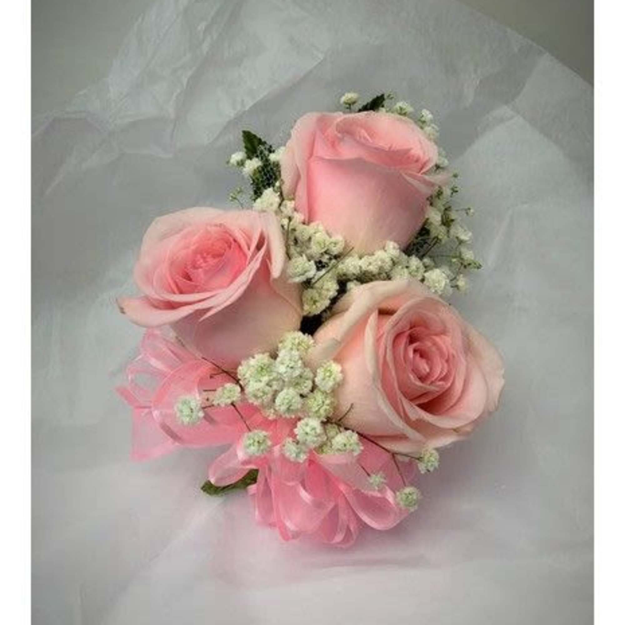 A classic pink wrist corsage hand-tied in pink satin ribbon that compliments
