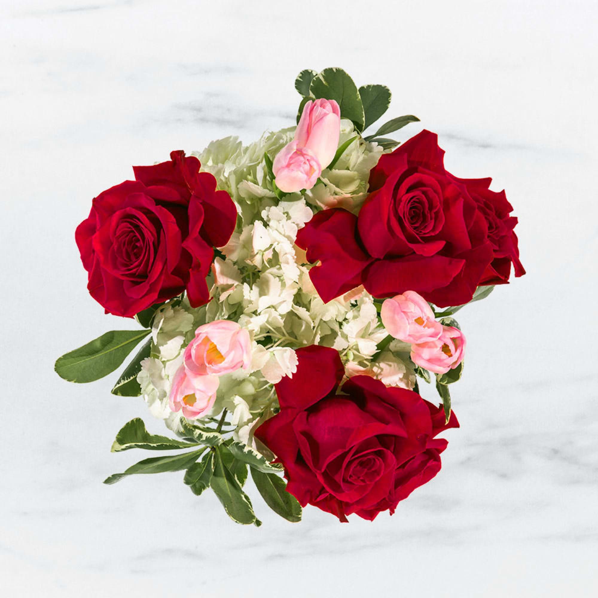 Top view of a round bouquet with red roses, pale pink blooms, and white hydrangeas.