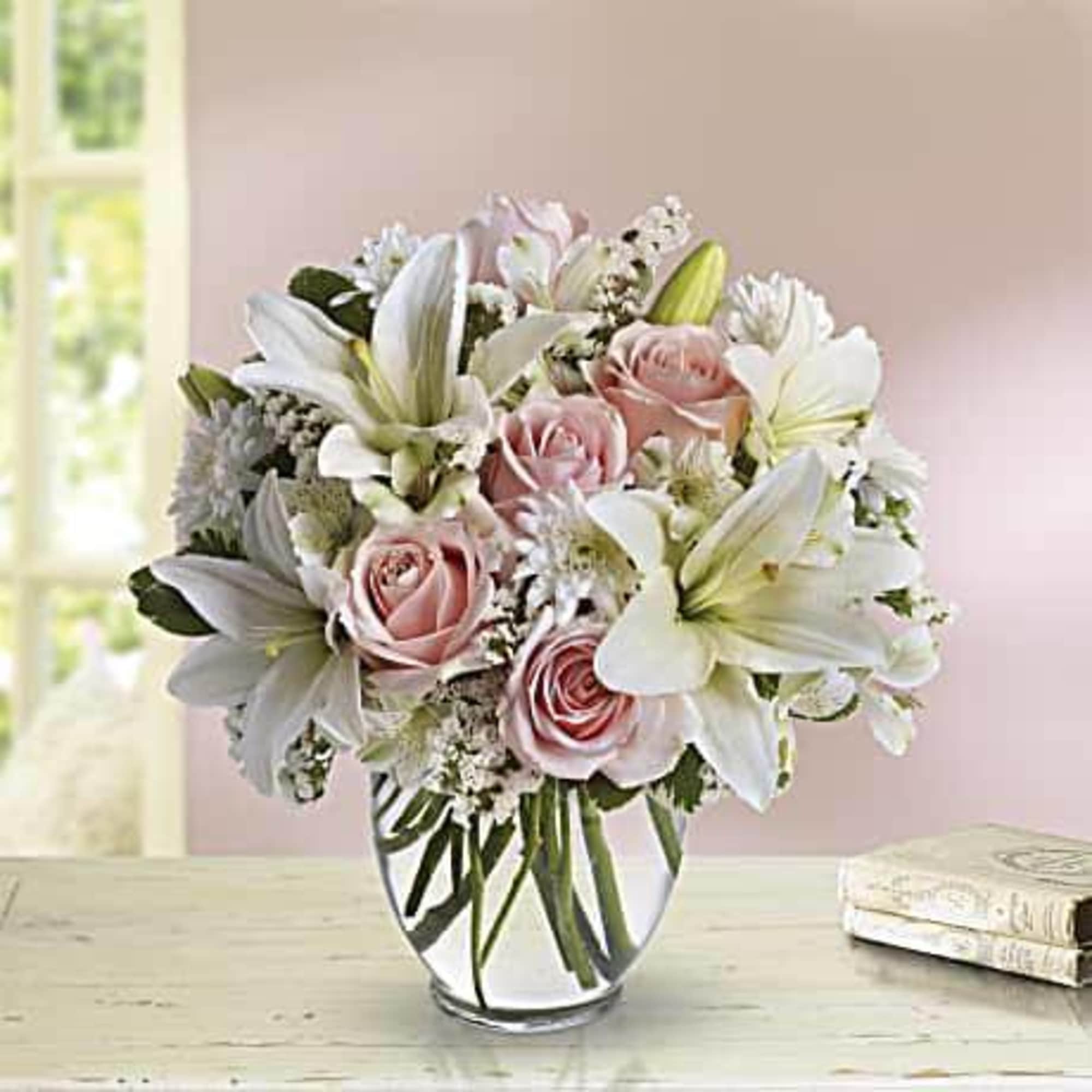 Bouquet of pink roses and white lilies in a clear glass vase