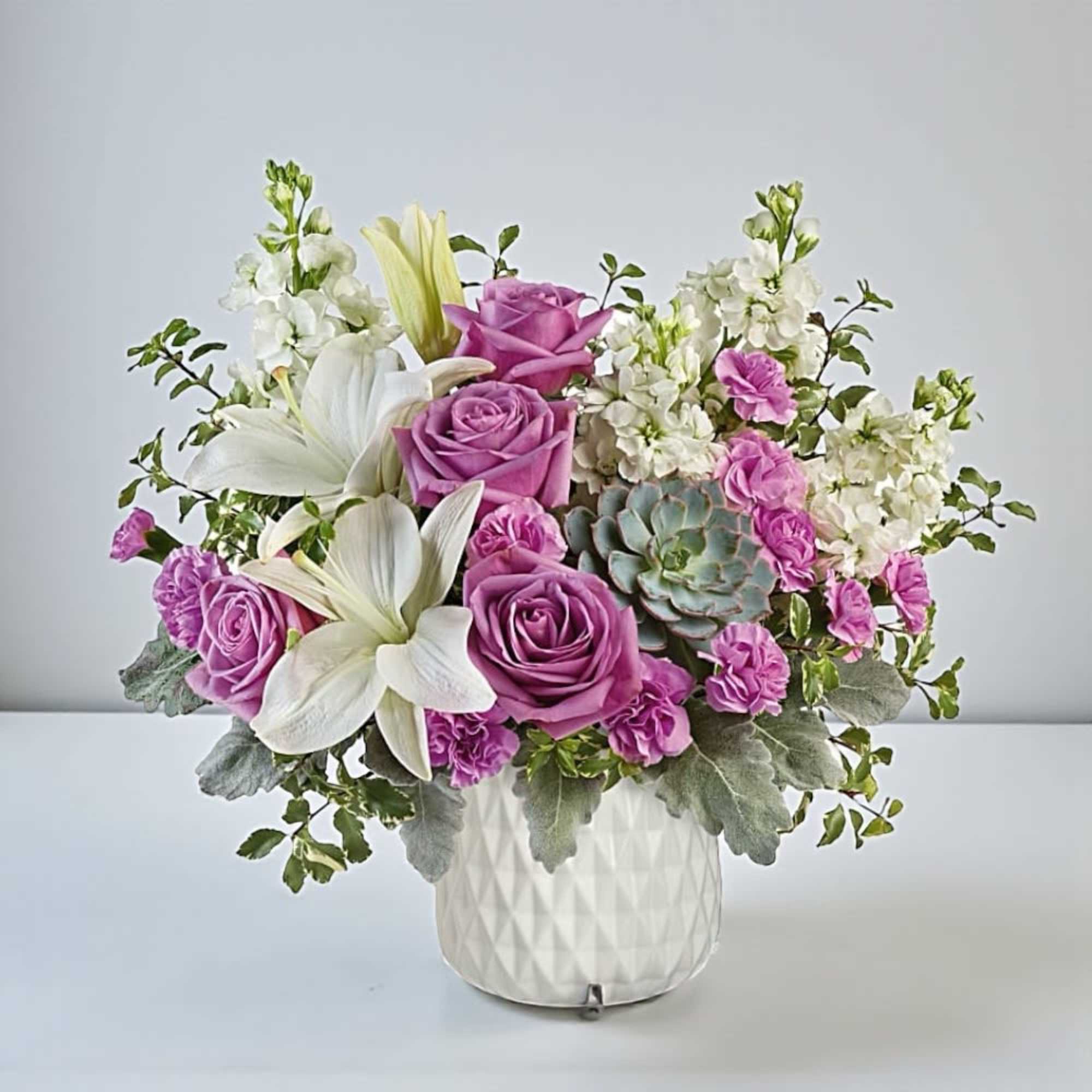 Bouquet of purple roses and white lilies in a white vase