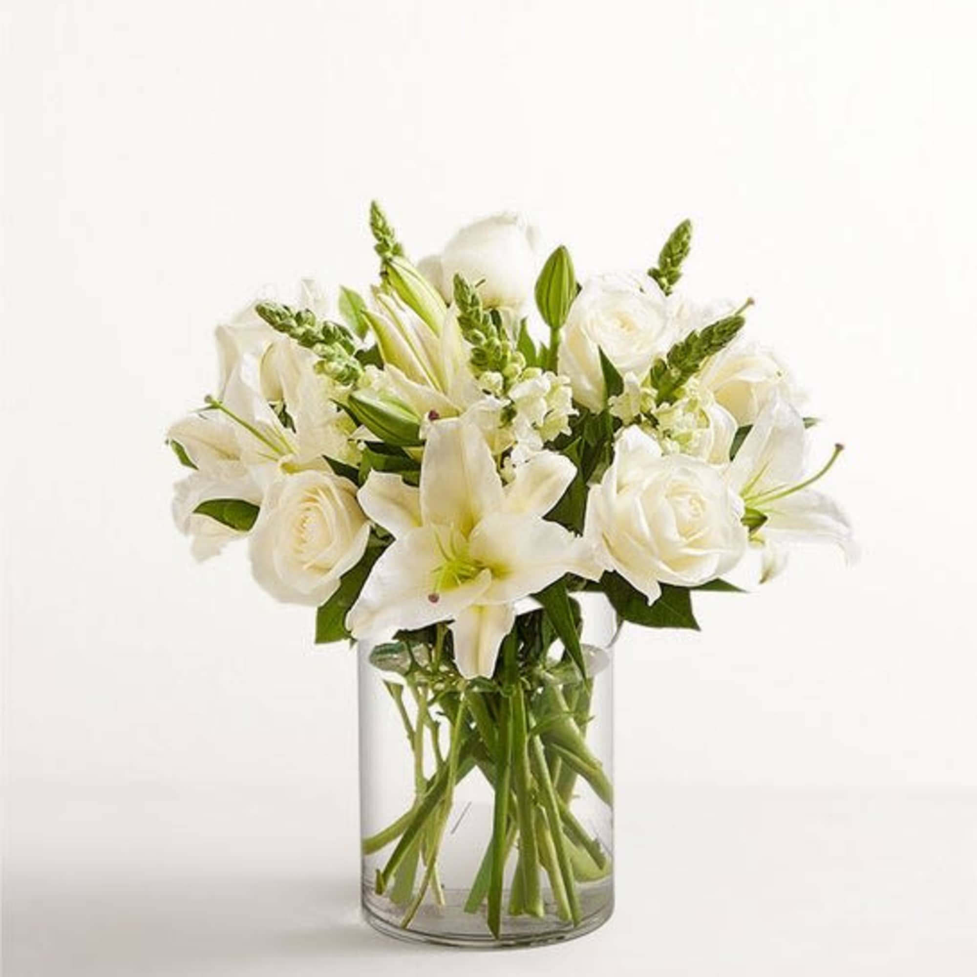 White lilies and roses arranged in a clear glass vase
