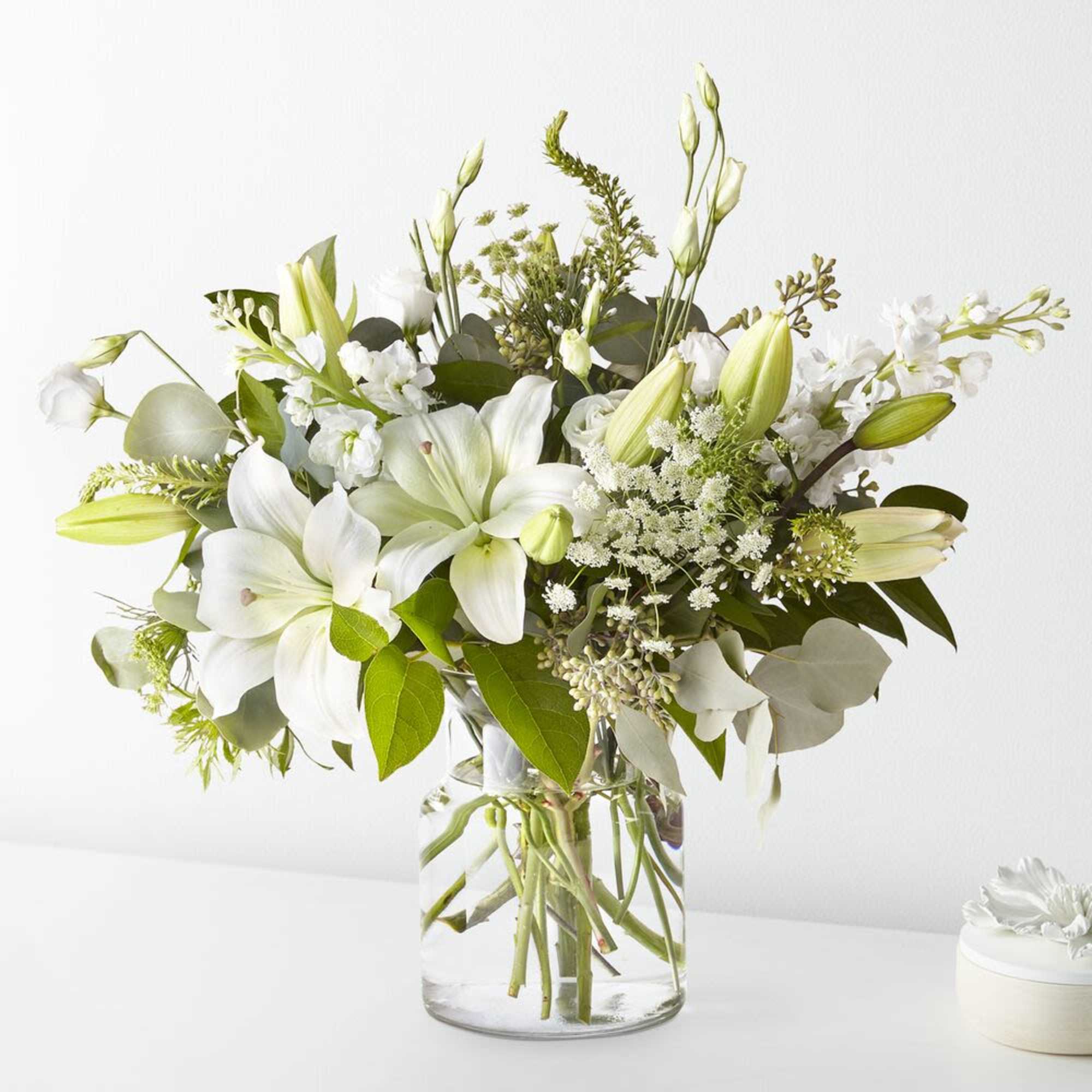 White lilies and orchids in a clear glass vase