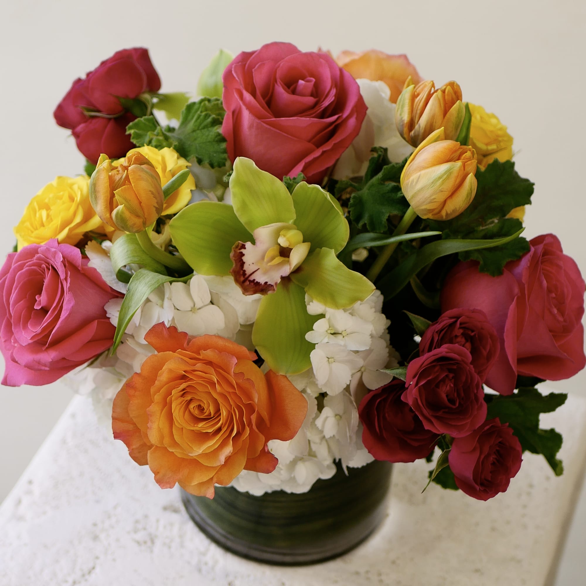 This vibrant arrangement brings together hot pink roses, orange roses, yellow spray