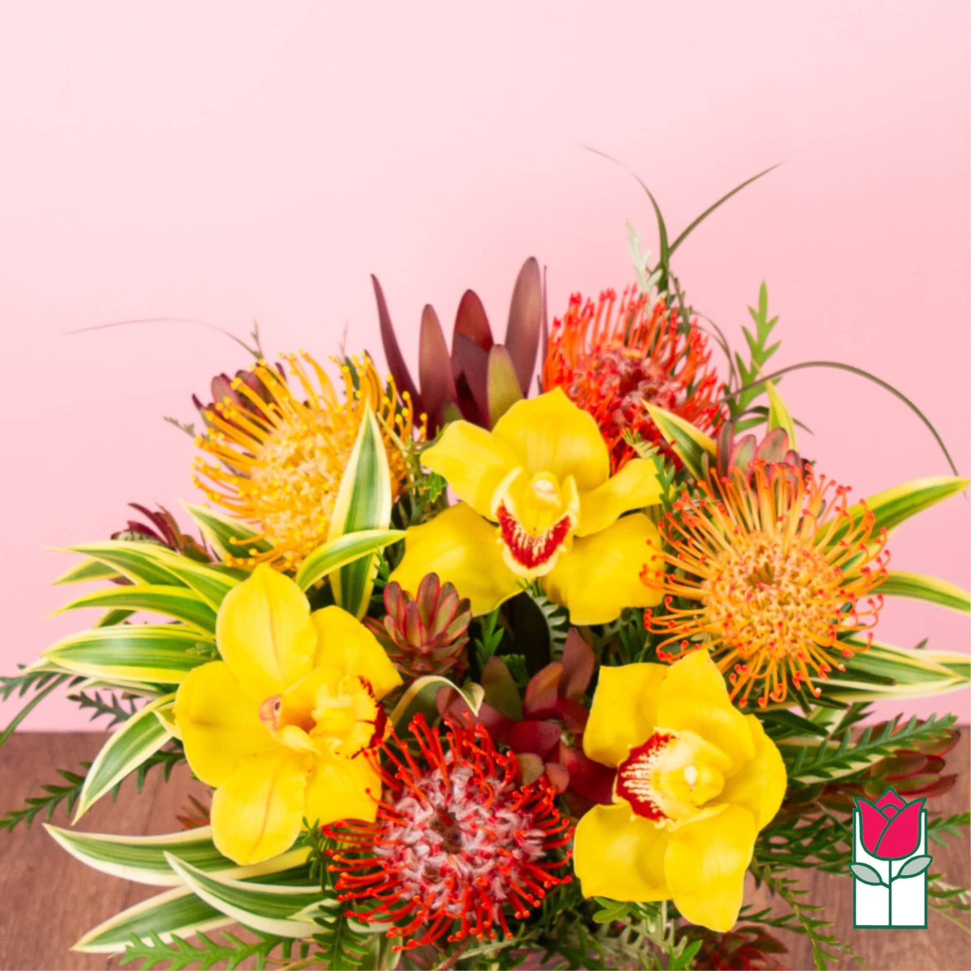 Tropical arrangement with yellow orchids and orange protea pincushions on a pink background.