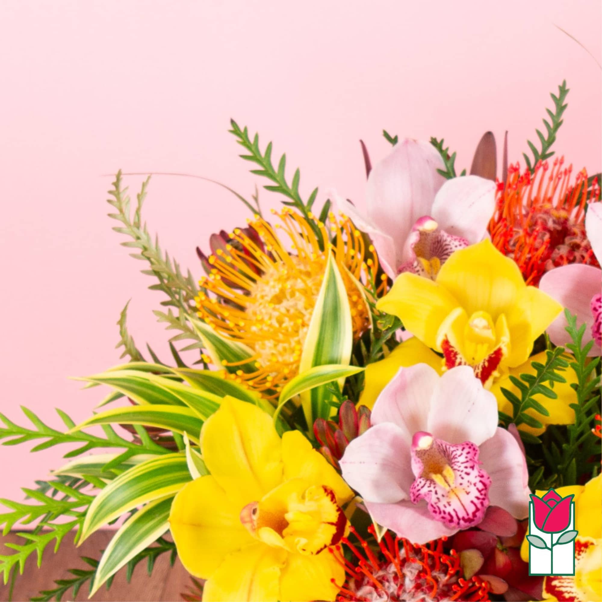 Bright tropical bouquet with yellow and pink orchids and orange pincushion blooms.